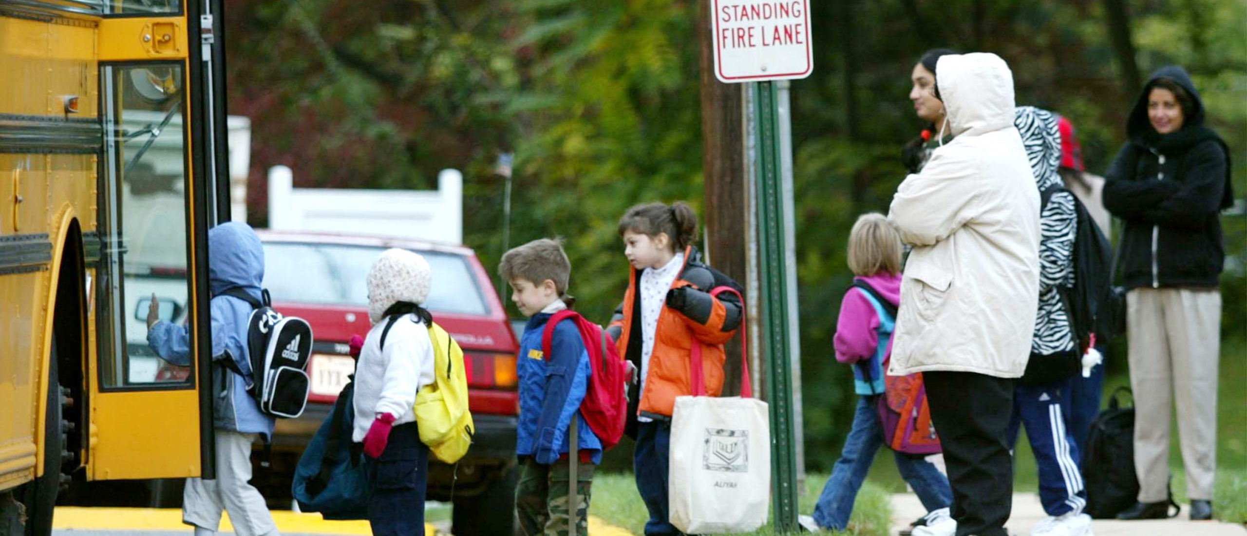 Parents watch as children step onto a Fairfax County school bus October 15, 2002, at Police headquarters in Falls Church, Virginia. Manger confirmed that the women who was shot and killed at the Home Depot store in Falls Church, Virginia was the work of the Beltway sniper. (Photo by Mark Wilson/Getty Images)