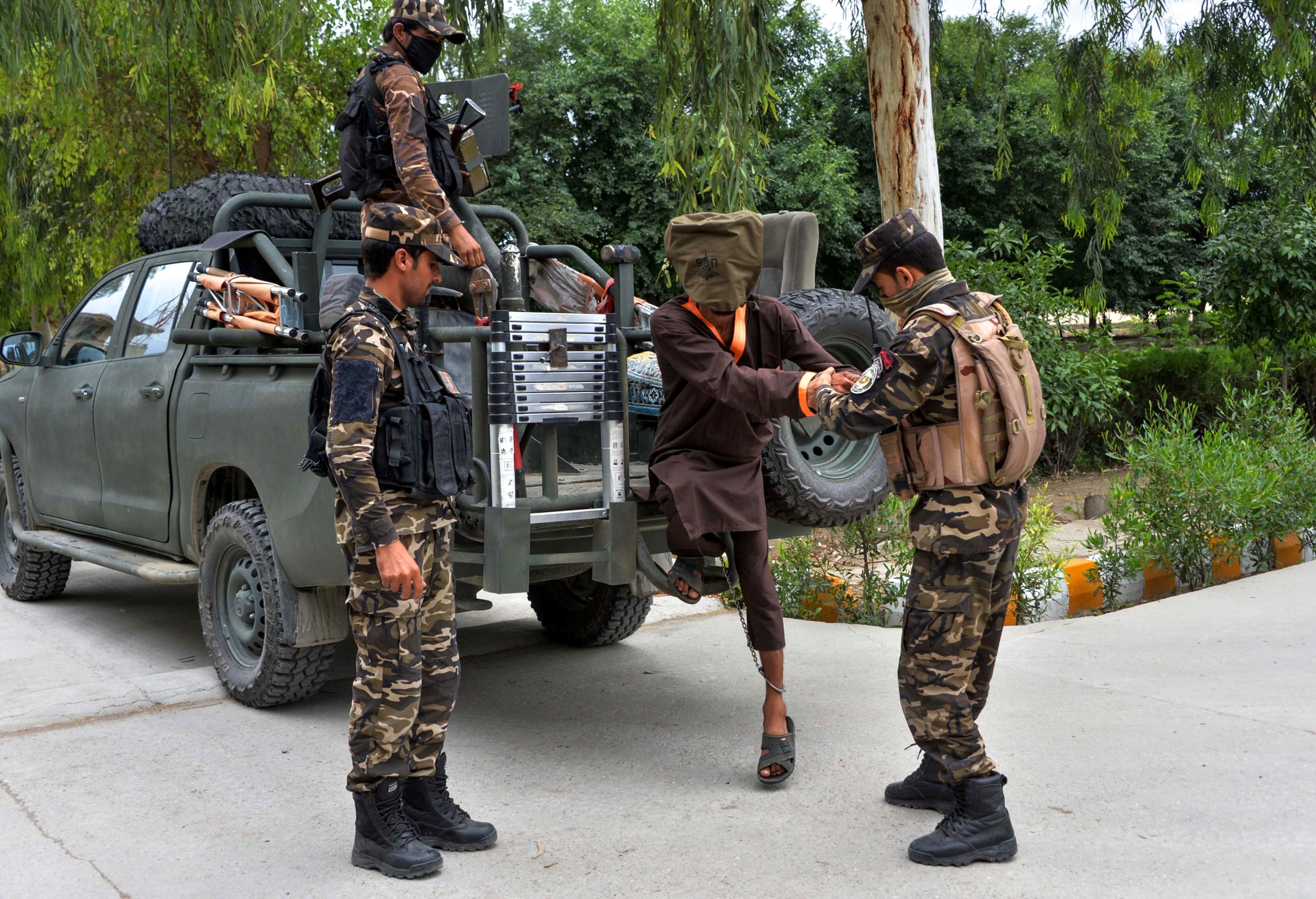 Forces with Afghanistan's National Directorate of Security (NDS) escort an alleged militant as Taliban and Islamic State (IS) fighters are presented to the media in Jalalabad on May 23, 2019. (Photo by NOORULLAH SHIRZADA / AFP) (Photo credit should read NOORULLAH SHIRZADA/AFP via Getty Images)