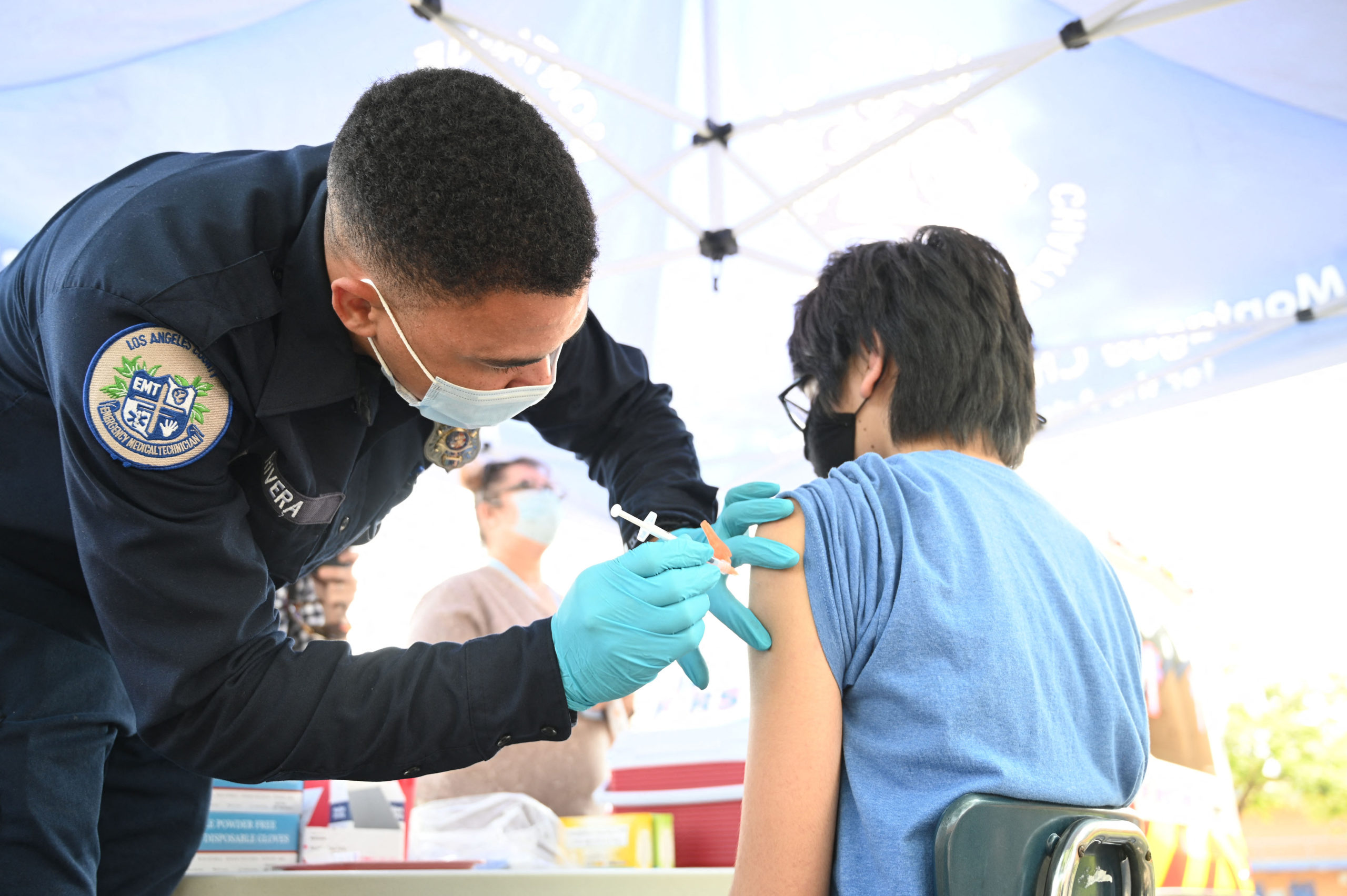 Brandon Rivera, a Los Angeles County emergency medical technician, gives a second does of Pfizer-BioNTech Covid-19 vaccine to Aaron Delgado, 16, at a pop up vaccine clinic in the Arleta neighborhood of Los Angeles, California, August 23, 2021. (ROBYN BECK/AFP via Getty Images)