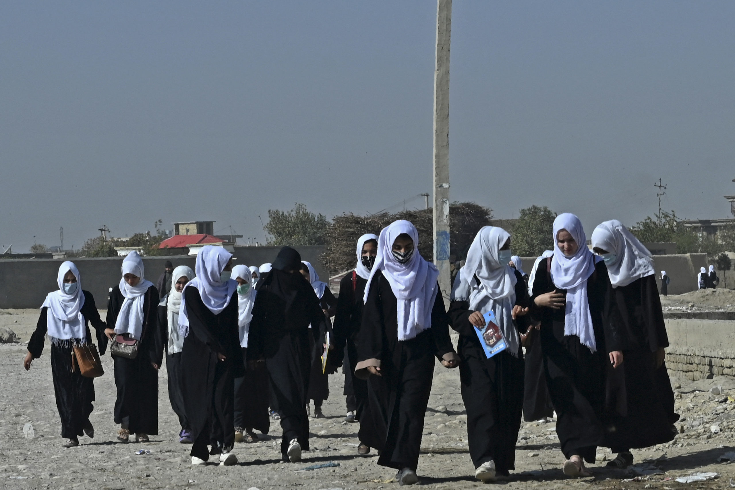Afghan schoolgirls walk along a path as they return from school in Mazar-i-Sharif on October 30, 2021. (Photo by WAKIL KOHSAR / AFP) (Photo by WAKIL KOHSAR/AFP via Getty Images)