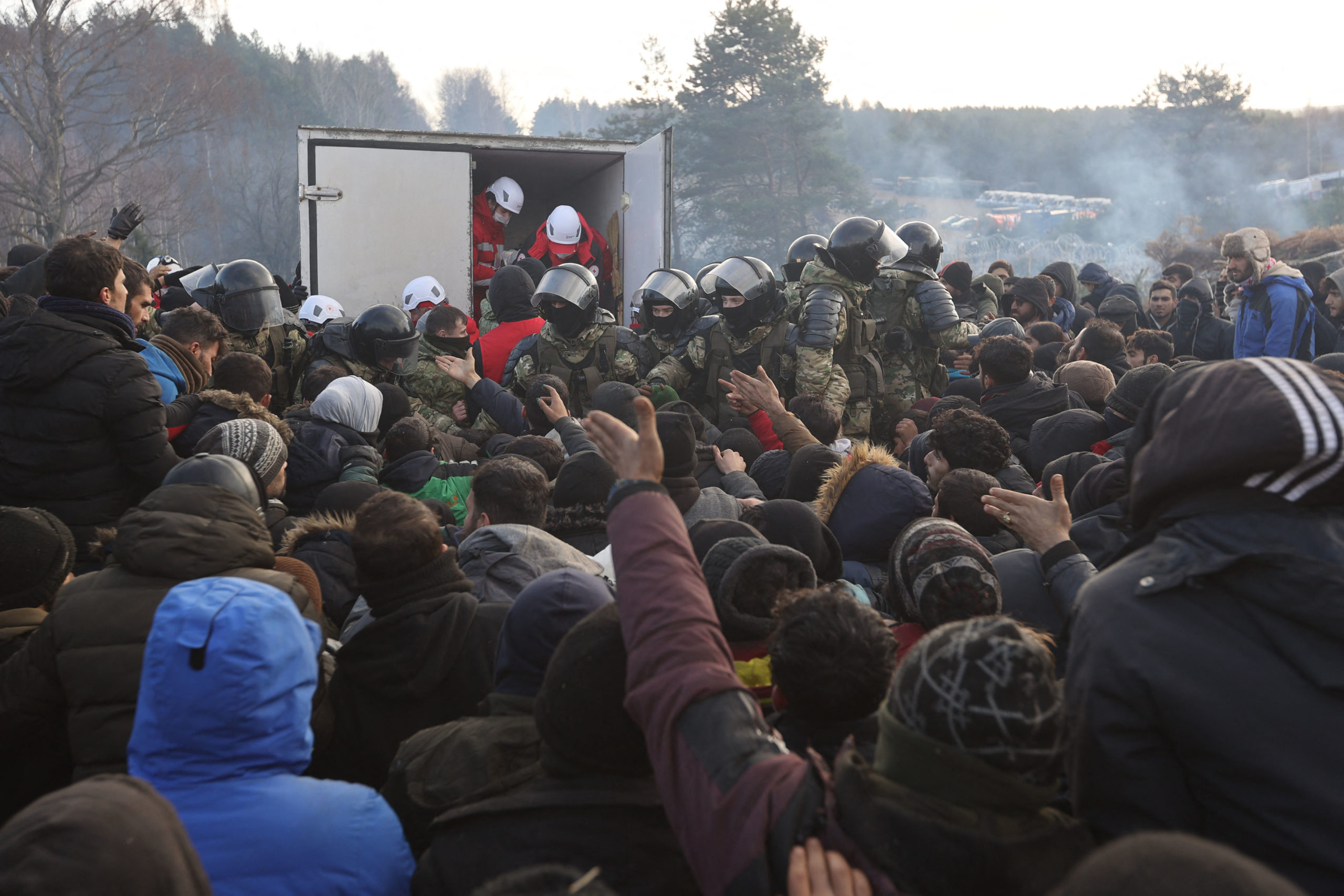 Migrants gather to receive humanitarian aid in a camp on the Belarusian-Polish border in the Grodno region on November 12, 2021. (Photo by RAMIL NASIBULIN/BELTA/AFP via Getty Images)