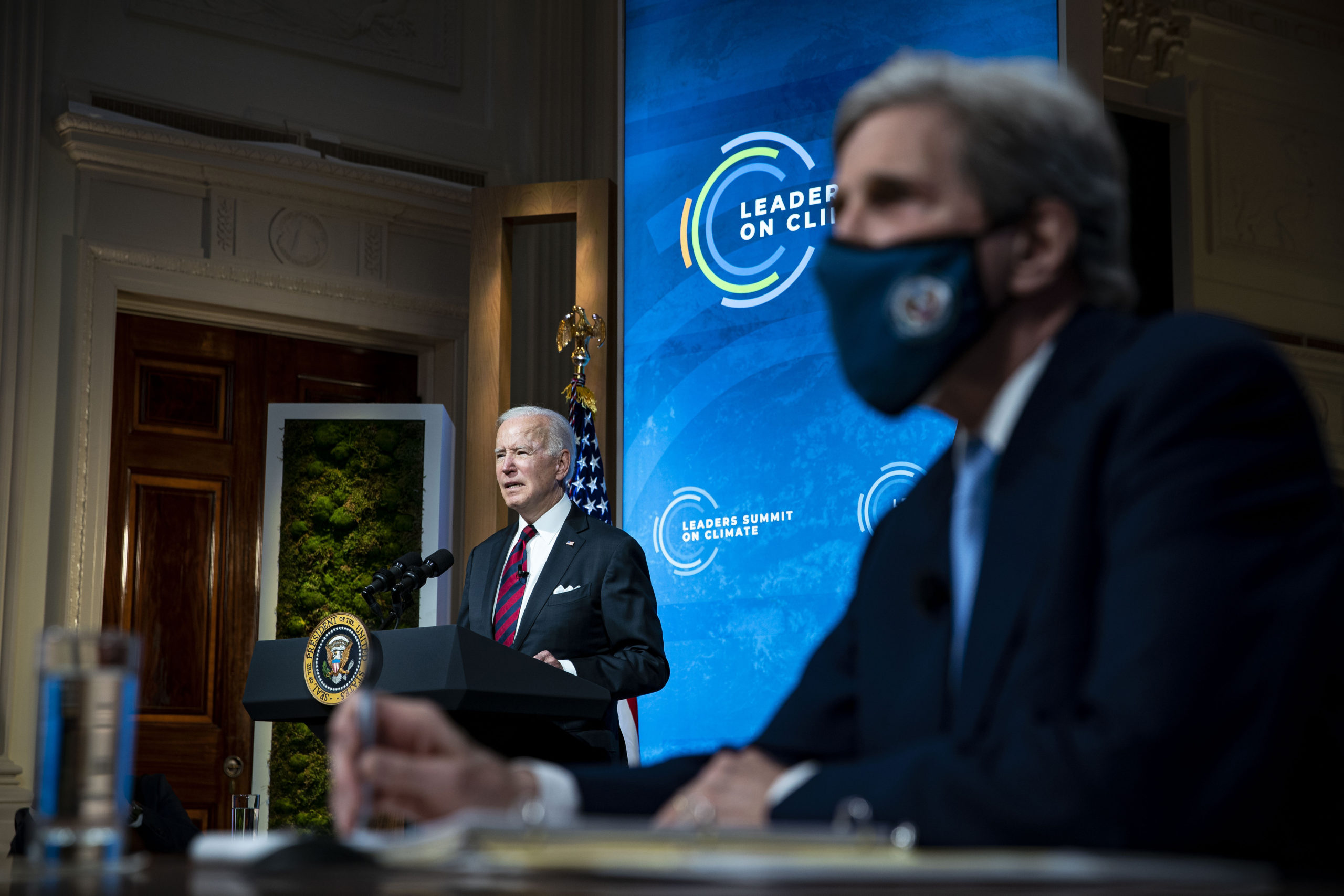 President Joe Biden delivers remarks as Special Presidential Envoy for Climate and former Secretary of State John Kerry listens during a virtual Leaders Summit on Climate in April. (Al Drago/Pool/Getty Images)