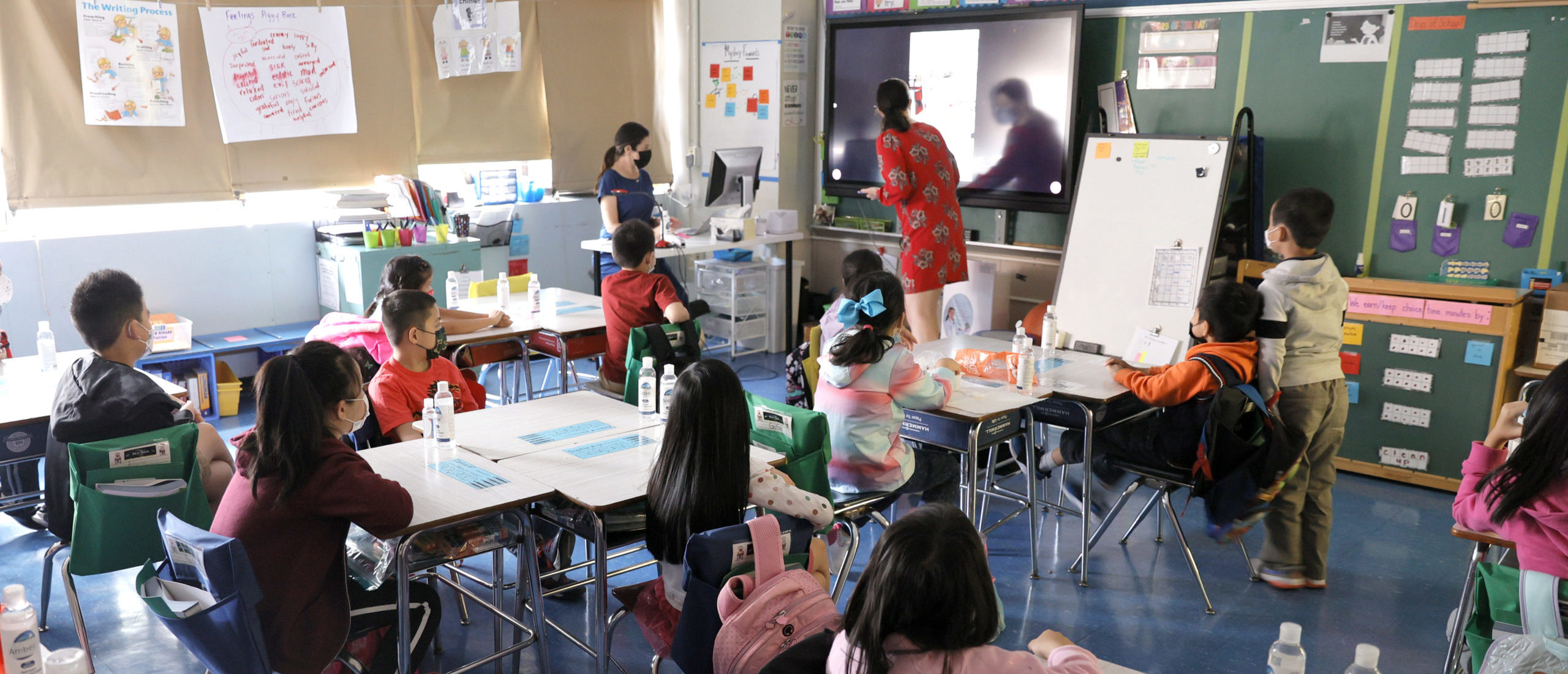 Co-teachers at Yung Wing School P.S. 124 Marisa Wiezel (who is related to the photographer) and Caitlin Kenny give a lesson to their masked students in their classroom on September 27, 2021 in New York City. (Photo by Michael Loccisano/Getty Images)