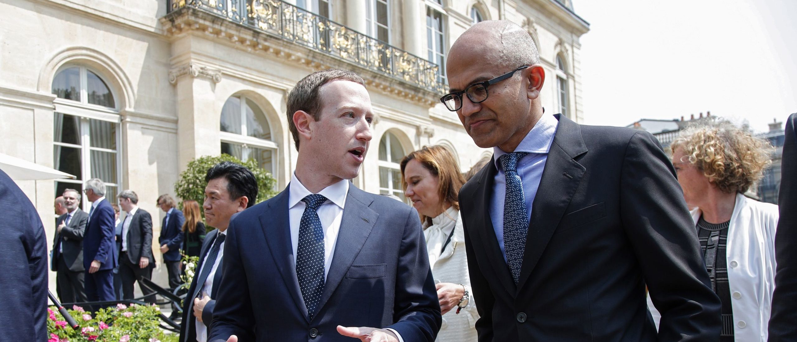TOPSHOT - Facebook's CEO Mark Zuckerberg (L) speaks with Microsoft's CEO Satya Nadella after posing for a family picture with guests who attend the "Tech for Good" Summit at the Elysee Palace in Paris, on May 23, 2018. (Photo by CHARLES PLATIAU / POOL / AFP) (Photo credit should read CHARLES PLATIAU/AFP via Getty Images)