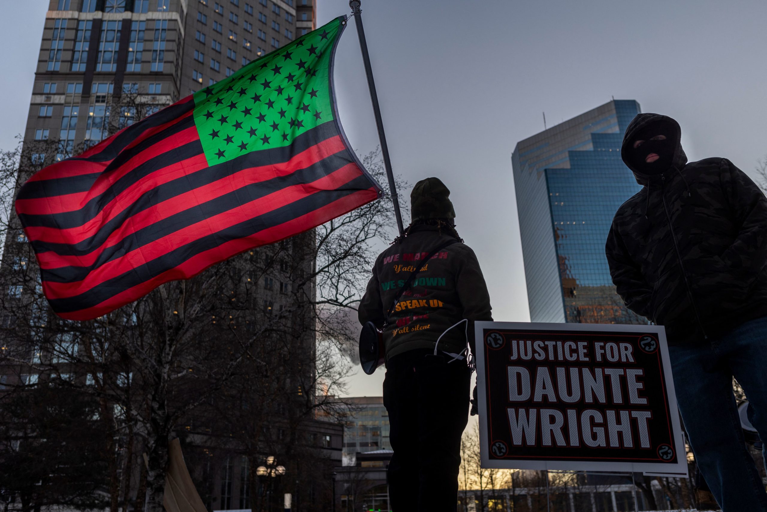 A man holds an African-American US National flag as people wait for the verdict in Kim Potter's trial over the fatal shooting of Daunte Wright, outside the Hennepin County Courthouse in Minneapolis, Minnesota on December 20, 2021. - Kim Potter, 49, is charged with first degree manslaughter over the fatal shooting of Daunte Wright, 20, in Brooklyn Center, a suburb of Minneapolis, Minnesota, in April 2021. (Photo by Kerem Yucel / AFP) (Photo by KEREM YUCEL/AFP via Getty Images)