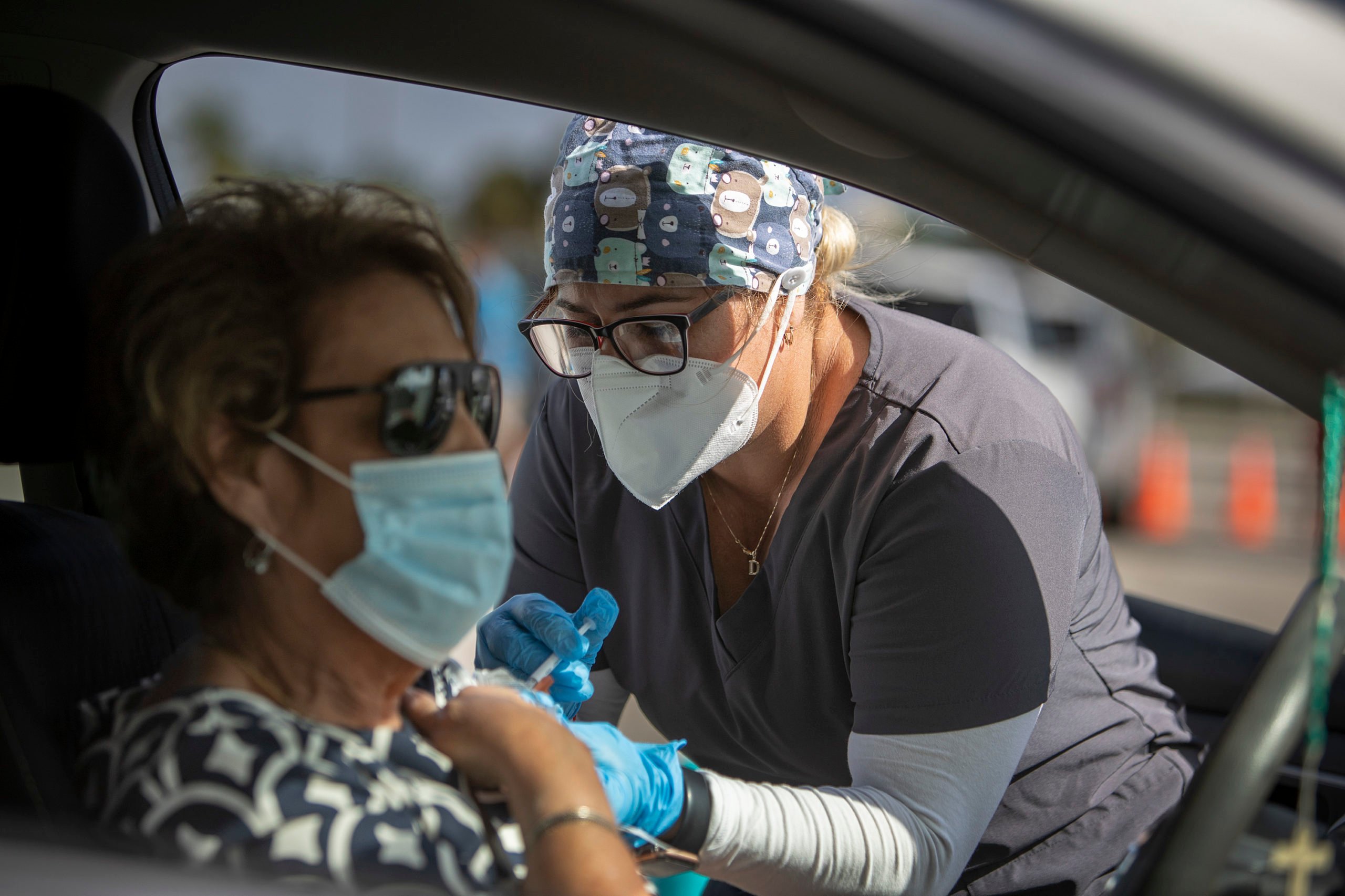 MIAMI, FLORIDA - DECEMBER 16: A healthcare worker administers a Pfizer-BioNTech COVID-19 vaccine to a person at a drive-thru site in Tropical Park on December 16, 2021 in Miami, Florida. Miami-Dade County Mayor Daniella Levine Cava visited the vaccination site to encourage residents to take holiday gatherings outside this year, get tested for COVID-19, and get vaccinated. (Photo by Joe Raedle/Getty Images)