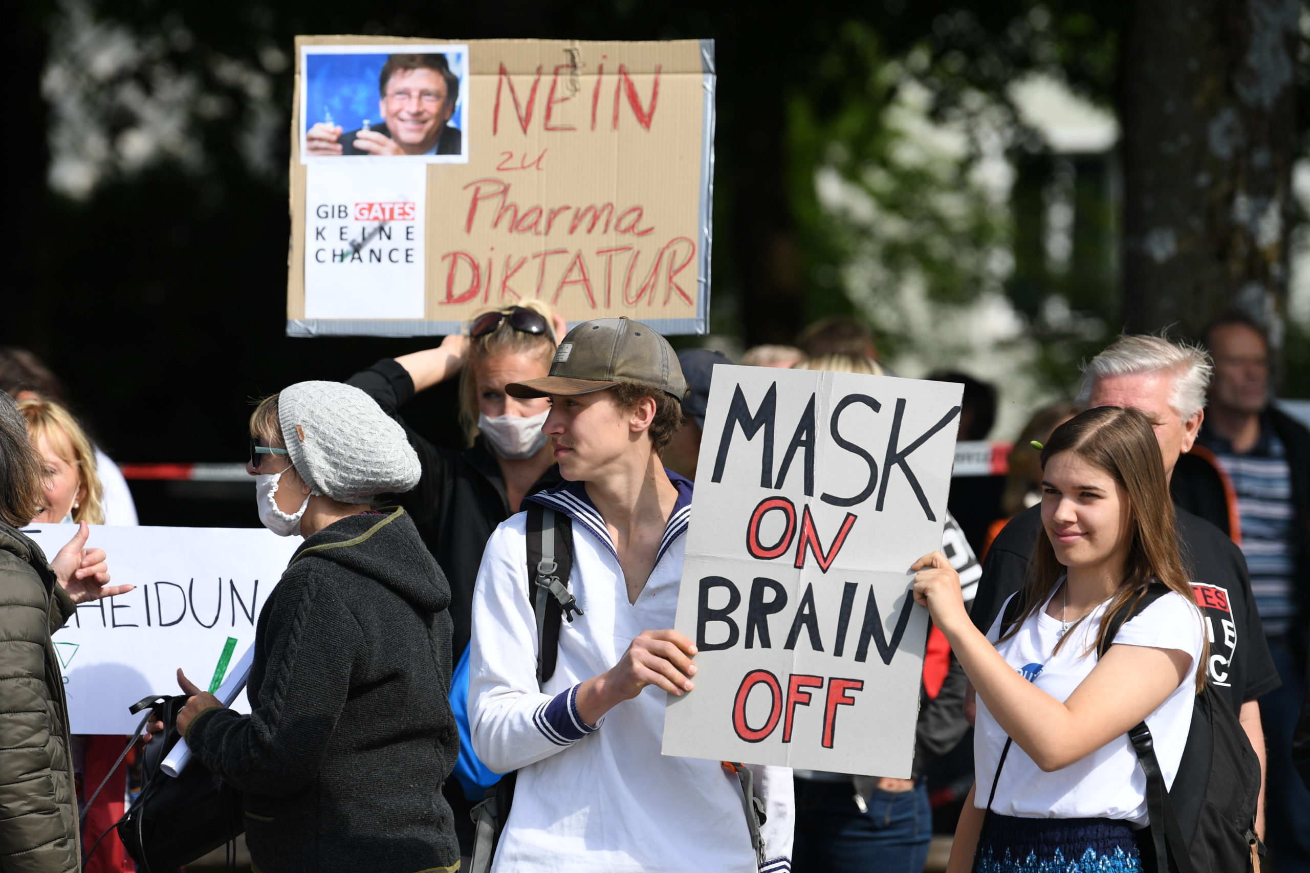 Protesters hold signs reading Mask on, brain off and I am not a conspirator, I am just a mother and Give Gates no chance during a protest of about 1000 people against lockdown measures and other government policies relating to the novel coronavirus crisis on May 16, 2020 in Munich, Germany. (Photo by Andreas Gebert/Getty Images)