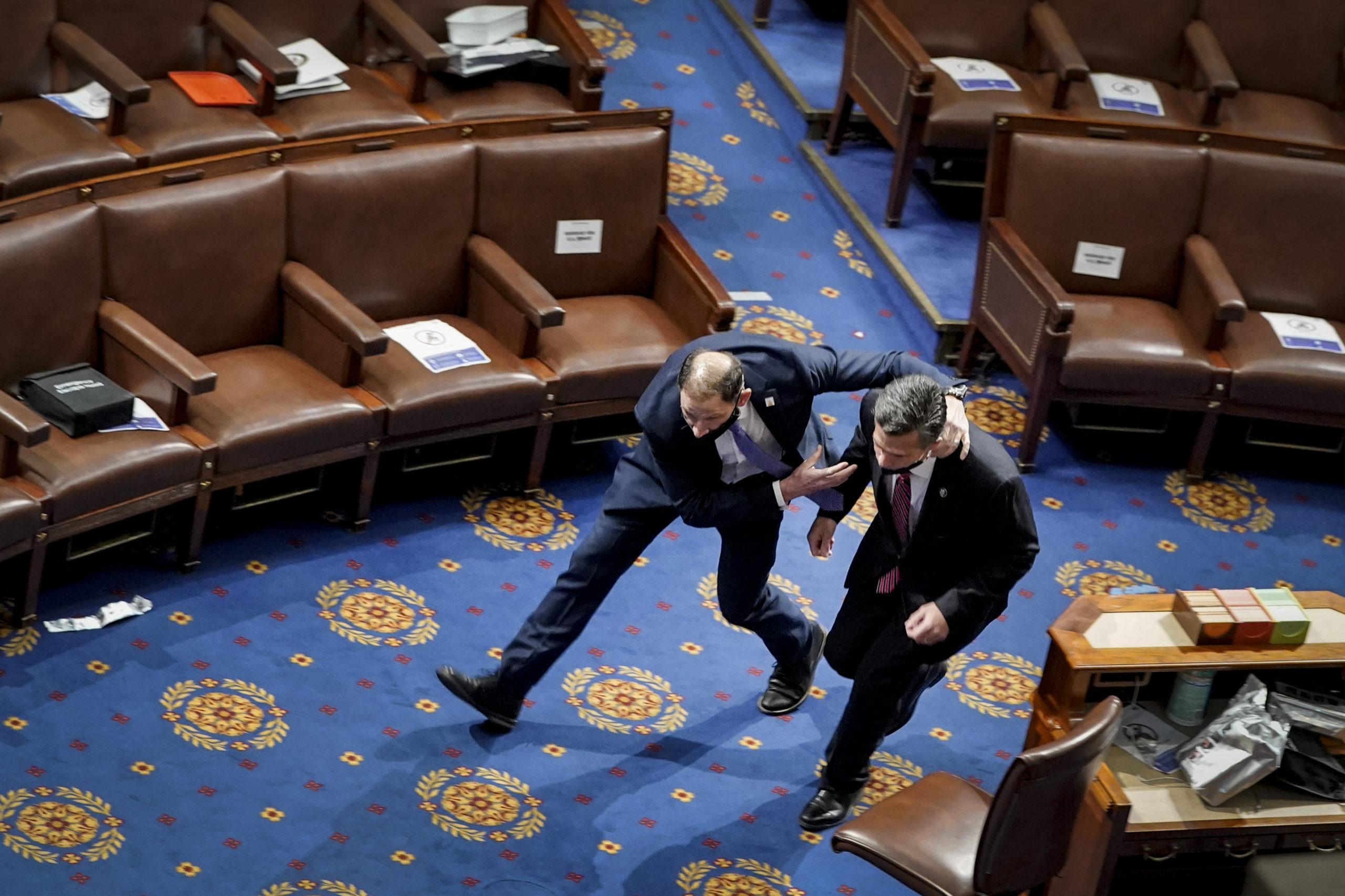 WASHINGTON, DC - JANUARY 06: A member of the U.S. Capitol police rushes Rep. Dan Meuser (R-PA) out of the House Chamber as protesters try to enter the House Chamber during a joint session of Congress on January 06, 2021 in Washington, DC. Congress held a joint session today to ratify President-elect Joe Biden's 306-232 Electoral College win over President Donald Trump. A group of Republican senators said they would reject the Electoral College votes of several states unless Congress appointed a commission to audit the election results. (Photo by Drew Angerer/Getty Images)