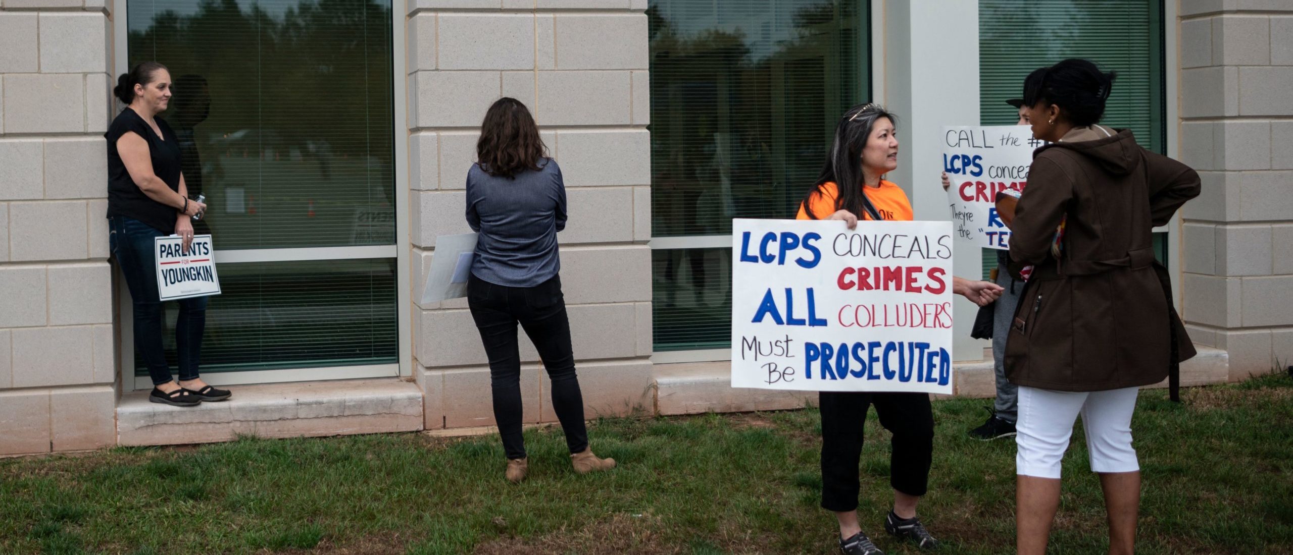 Protesters and activists hold signs as they stand outside a Loudoun County Public Schools (LCPS) board meeting in Ashburn, Virginia on October 12, 2021. (Photo by ANDREW CABALLERO-REYNOLDS/AFP via Getty Images)