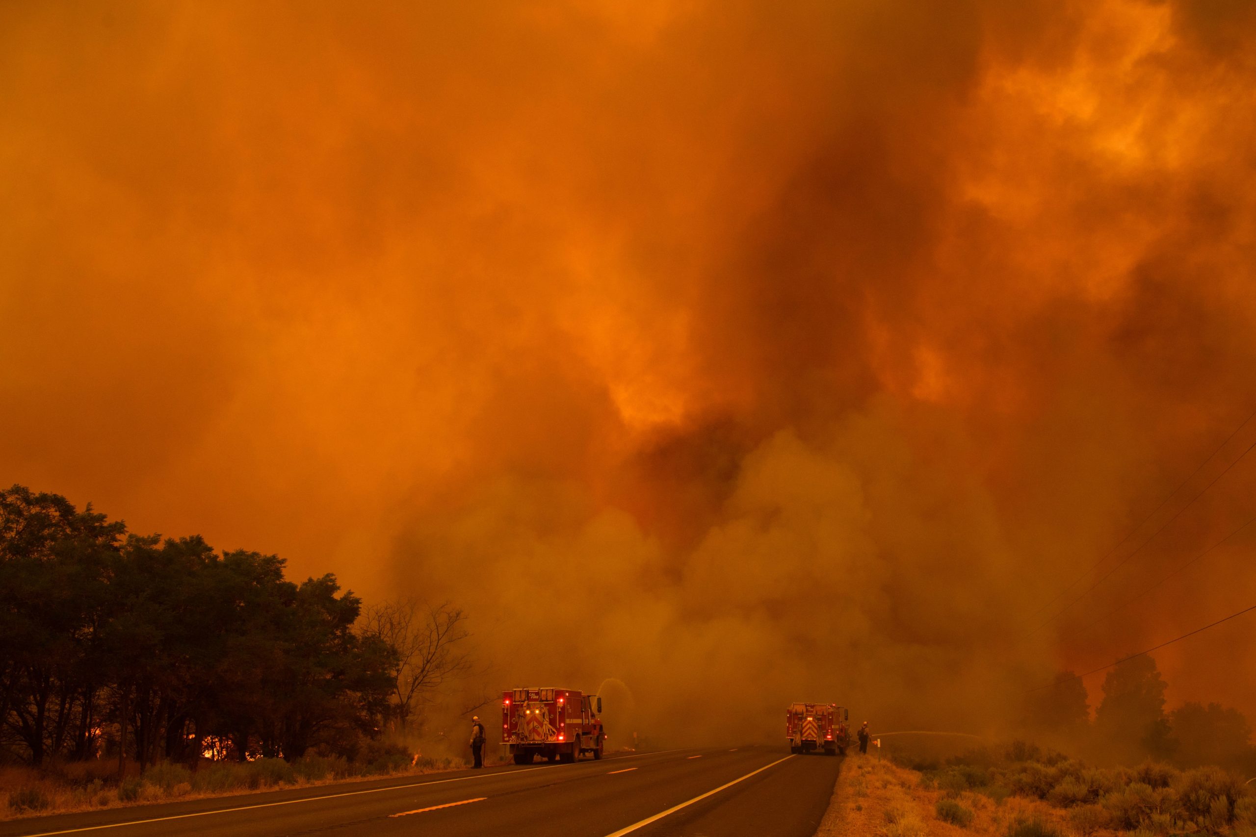 Flames and smoke plume into the air as firefighters try to contain the fire from spotting across Highway 395 during the Dixie Fire on August 17, 2021 near Milford, California. (Photo by PATRICK T. FALLON/AFP via Getty Images)