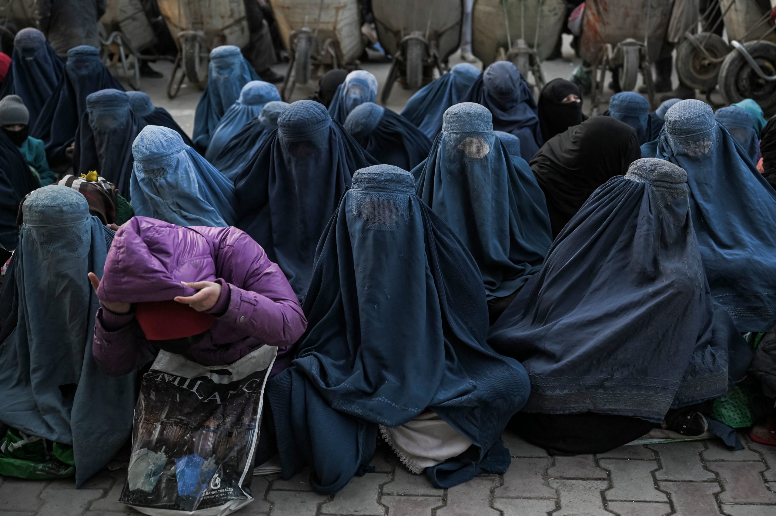 Women wearing a burqa wait for free bread in front of a bakery in Kabul on January 24, 2022. (Photo by Mohd RASFAN / AFP) (Photo by MOHD RASFAN/AFP via Getty Images)