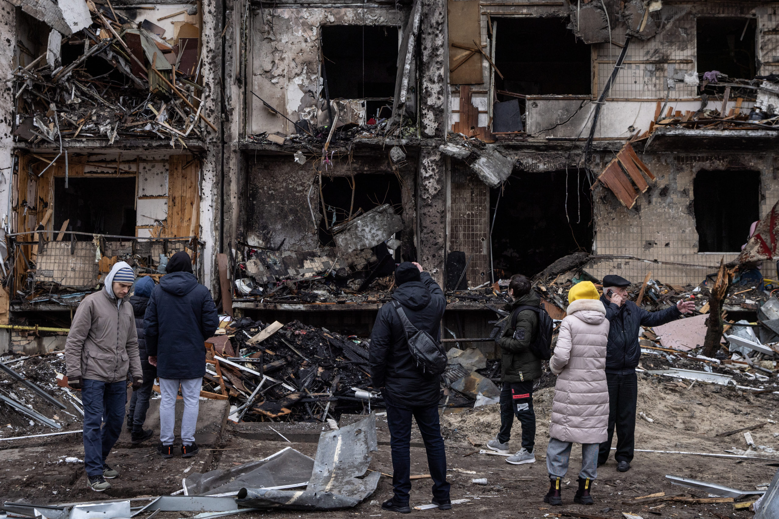 People look at the exterior of a damaged residential block hit by an early morning missile strike on Feb. 25 in Kyiv, Ukraine. (Chris McGrath/Getty Images)