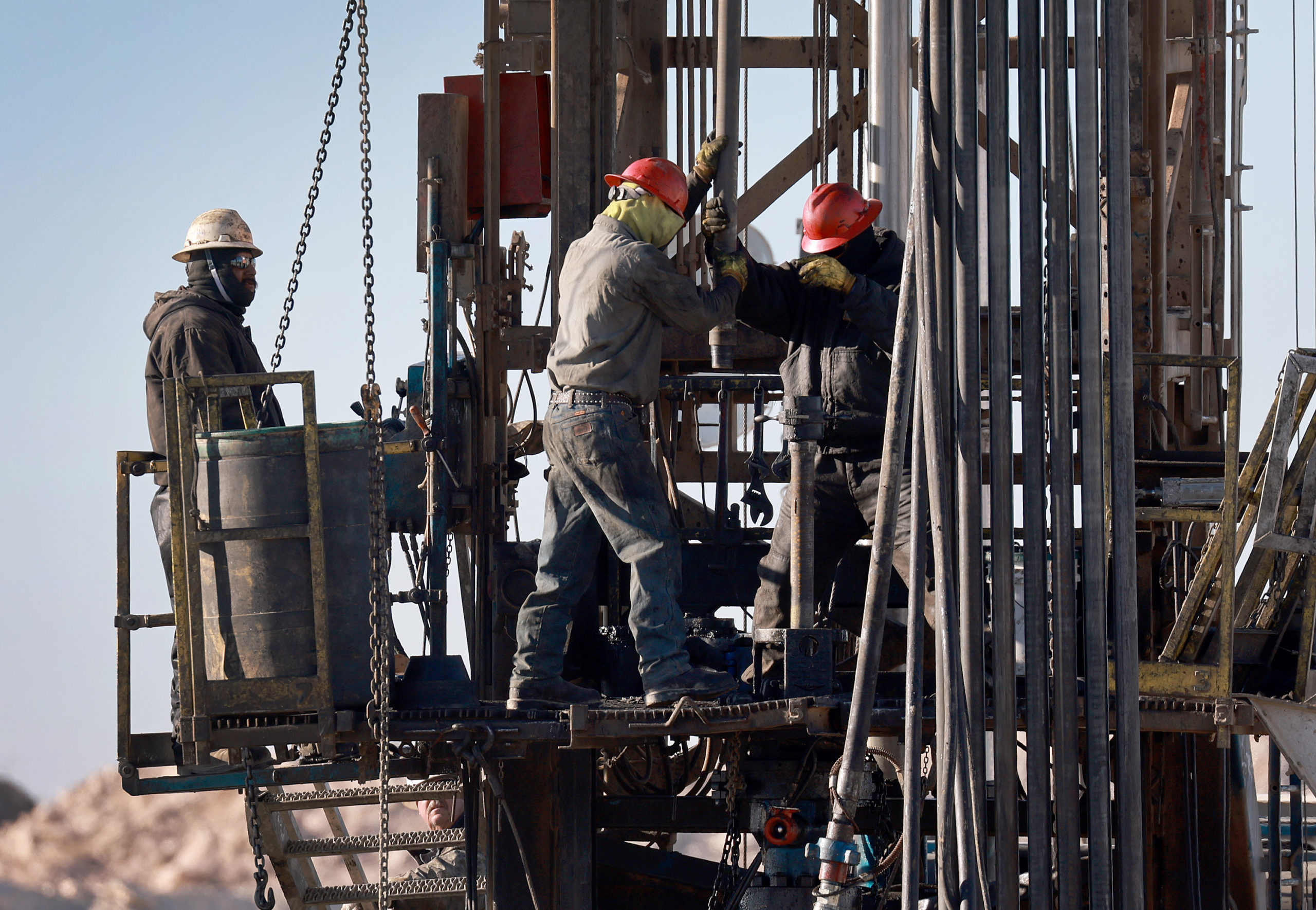 Workers place pipe into the ground on an oil drilling rig set up in the Permian Basin oil field on March 12 in Midland, Texas. (Joe Raedle/Getty Images)