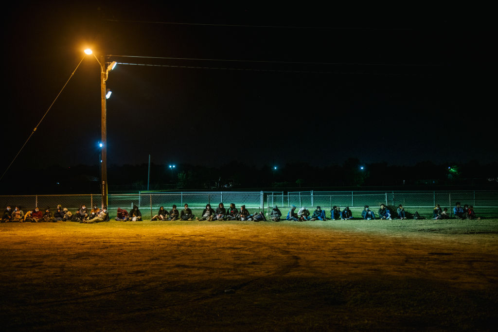 LA JOYA, TEXAS - NOVEMBER 17: Migrants sit against a fence while waiting to board a border patrol bus after crossing the Rio Grande into the U.S. on November 17, 2021 in La Joya, Texas. The number of migrants taken into U.S. custody along the southern border decreased for a third consecutive month in October. U.S. Customs and Border Protection (CBP) recorded more than 164,000 migrant apprehensions in October. Approximately 55% of migrants encountered were expelled back to Mexico, or their homelands. U.S. President Joe Biden is set to have a meeting this Thursday with Mexican President Andrés Manuel López Obrador, and Canadian Prime Minister Justin Trudeau where they will discuss the coronavirus pandemic, climate change, immigration and economic growth. (Photo by Brandon Bell/Getty Images)
