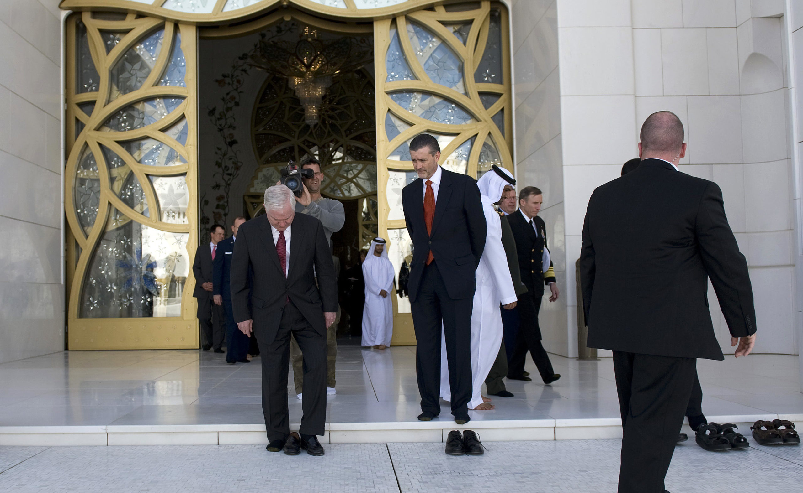 U.S Defense Secretary Robert Gates (L) and U.S Ambassador to the UAE Richard Olson (centre R) put on their shoes after touring through Sheikh Zayed Mosque in Abu Dhabi March 11, 2010.