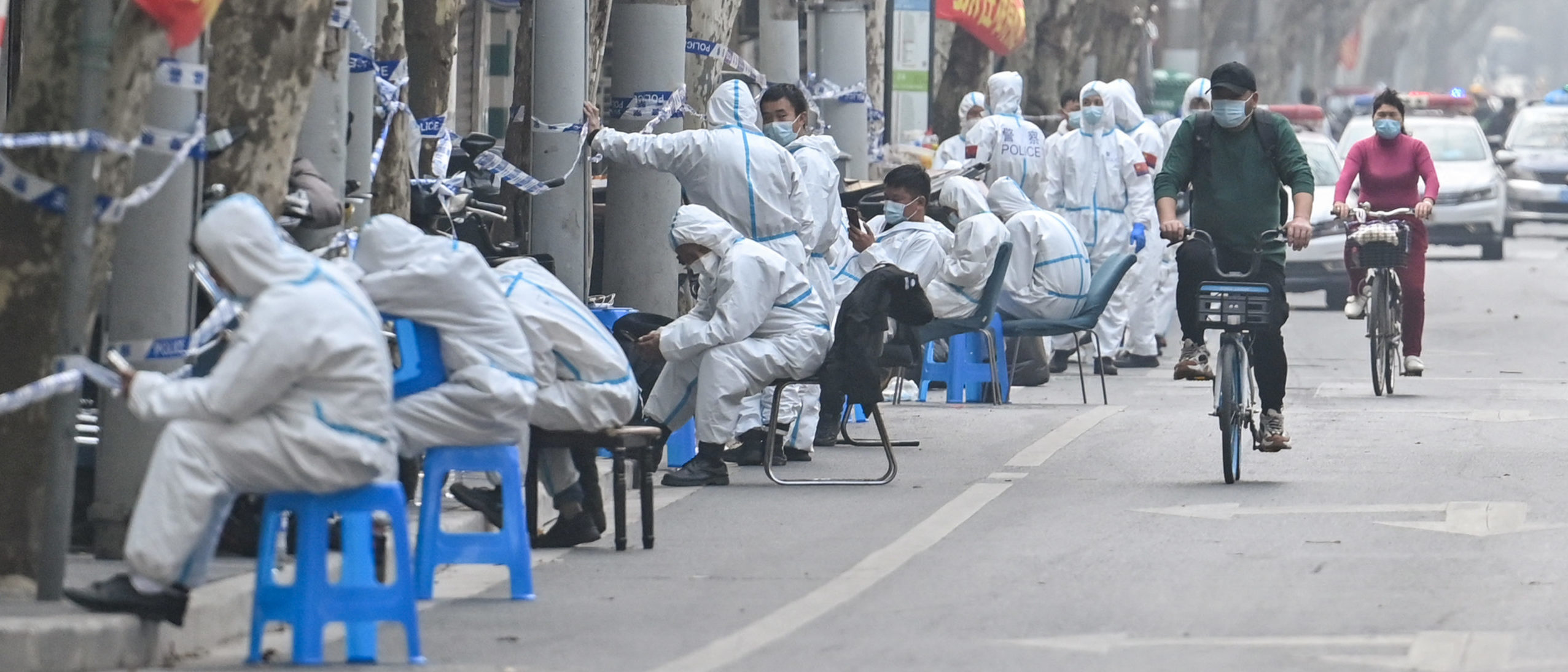 TOPSHOT - Workers are seen wearing protective clothes next to some lockdown areas after the detection of new cases of covid-19 in Shanghai on March 14, 2022 (Photo by Hector RETAMAL / AFP) (Photo by HECTOR RETAMAL/AFP via Getty Images)