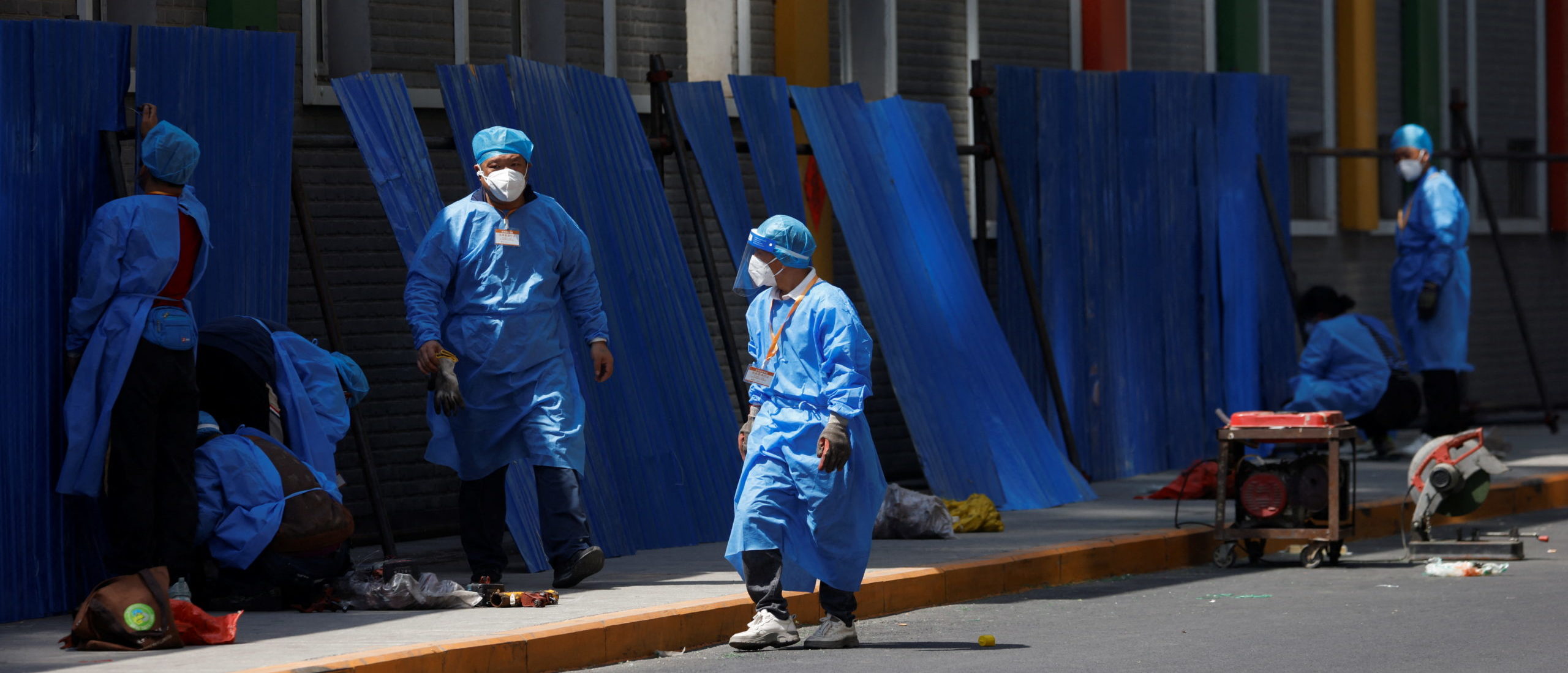 Workers wearing personal protective equipment (PPE), install a barricade around a residential area under lockdown, amid the coronavirus disease (COVID-19) outbreak in Beijing, China, May 4, 2022. (REUTERS/Carlos Garcia Rawlins)