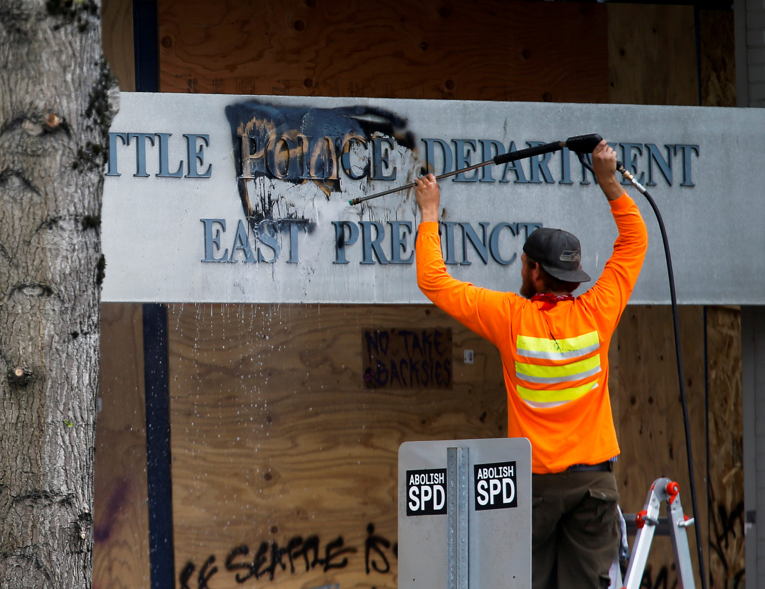 A worker cleans off the word "people" graffitied over the word "police" at the Seattle Police Department's East Precinct as they retake the Capitol Hill Occupied Protest (CHOP) area, in Seattle, Washington, U.S. July 1, 2020.