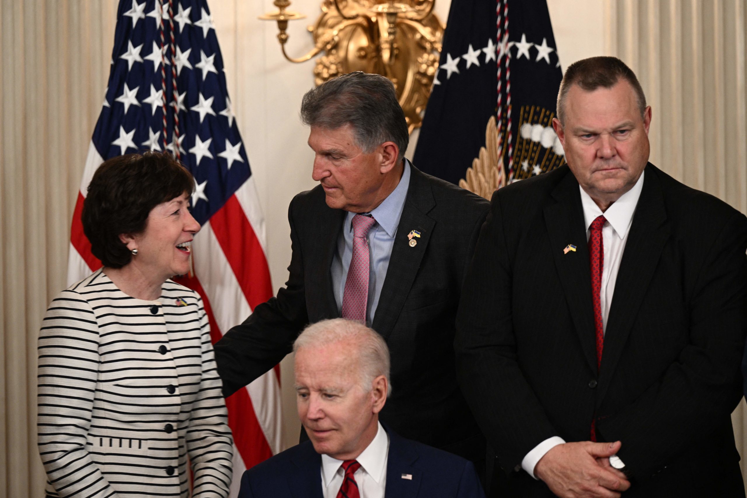 (L-R) US Senator Susan Collins (R-ME), US Senator Joe Manchin (D-WV), and US Senator Jon Tester (D-MT) stand behind US President Joe Biden during a signing ceremony in the State Dining Room of the White House in Washington, DC, on June 7, 2022. (Photo by BRENDAN SMIALOWSKI/AFP via Getty Images)