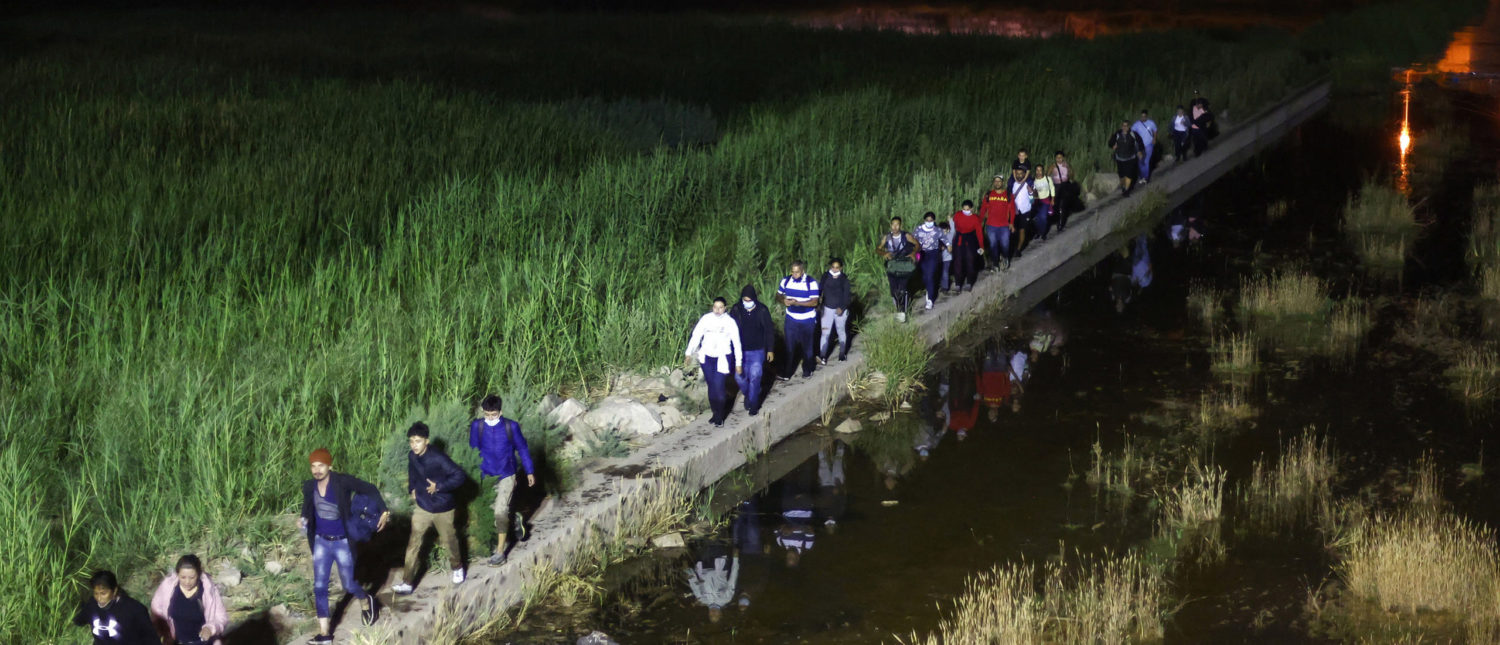 Immigrants walk from Mexico into the United States on their way to await processing by the U.S. Border Patrol on May 23, 2022 in Yuma, Arizona. (Mario Tama/Getty Images/TNS)