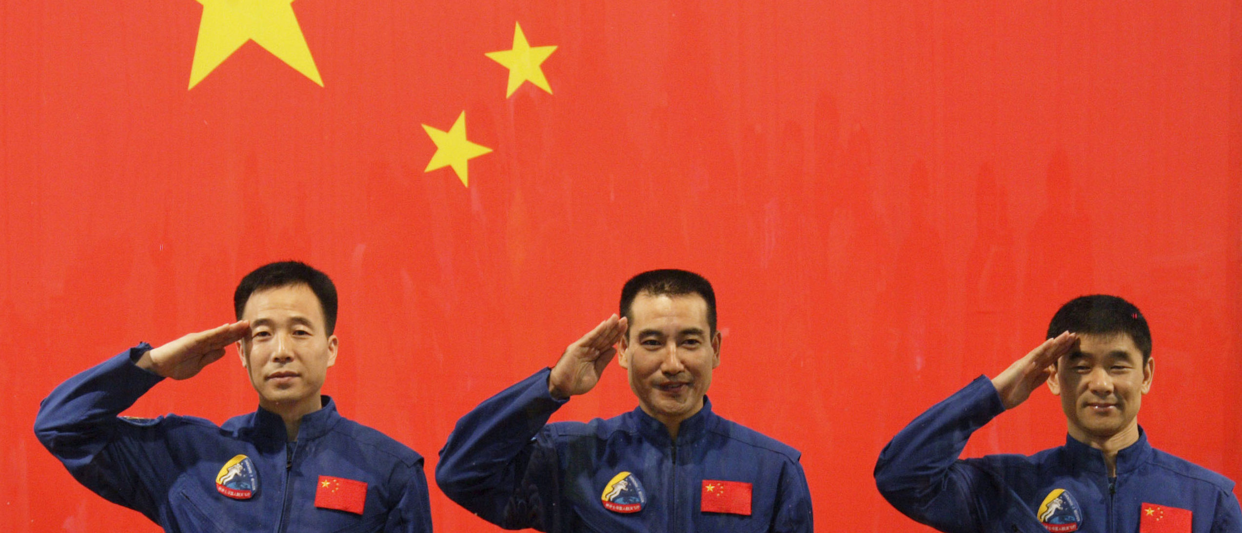 Chinese astronauts Jing Haipeng (L), Zhai Zhigang (C) and Liu Boming salute in front of a Chinese national flag during a news conference at the Jiuquan Satellite Launch Center, Gansu province September 24, 2008. China readied for its next leap into space on Thursday, with the Shenzhou VII craft primed to blast off with three astronauts and plans for a first space walk that will underscore the country's technological ambitions. Picture taken September 24, 2008. (REUTERS/Stringer)