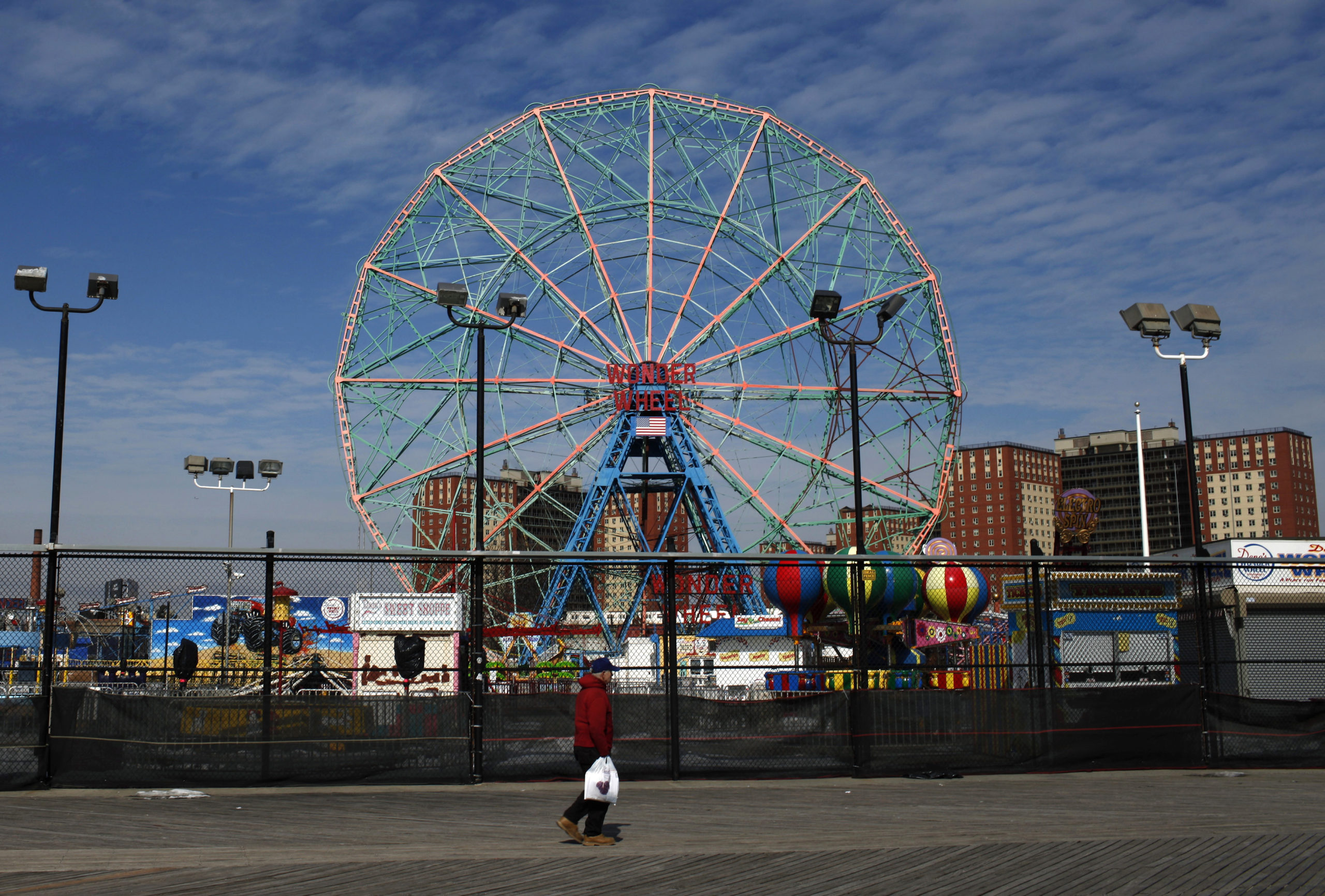 A man walks past the Wonder Wheel ride and an amusement part on the seaside Coney Island Boardwalk in the Brooklyn Borough of New York City February 26, 2015. Three men were charged on Wednesday with conspiring to support Islamic State, including two who planned to travel to Syria to fight on behalf of the radical group, U.S. authorities said. The suspects, all of three of whom lived in Brooklyn, were identified as Akhror Saidakhmetov, 19, a Kazakh national, Abdurasul Hasanovich Juraboev, 24 and Abror Habibov, 30, both from Uzbekistan. Police allege the suspects discussed carrying out attacks in the US, including shooting police officers and planting a bomb on New York's Coney Island seaside resort. REUTERS/Mike Segar (UNITED STATES - Tags: CITYSCAPE CIVIL UNREST CRIME LAW)