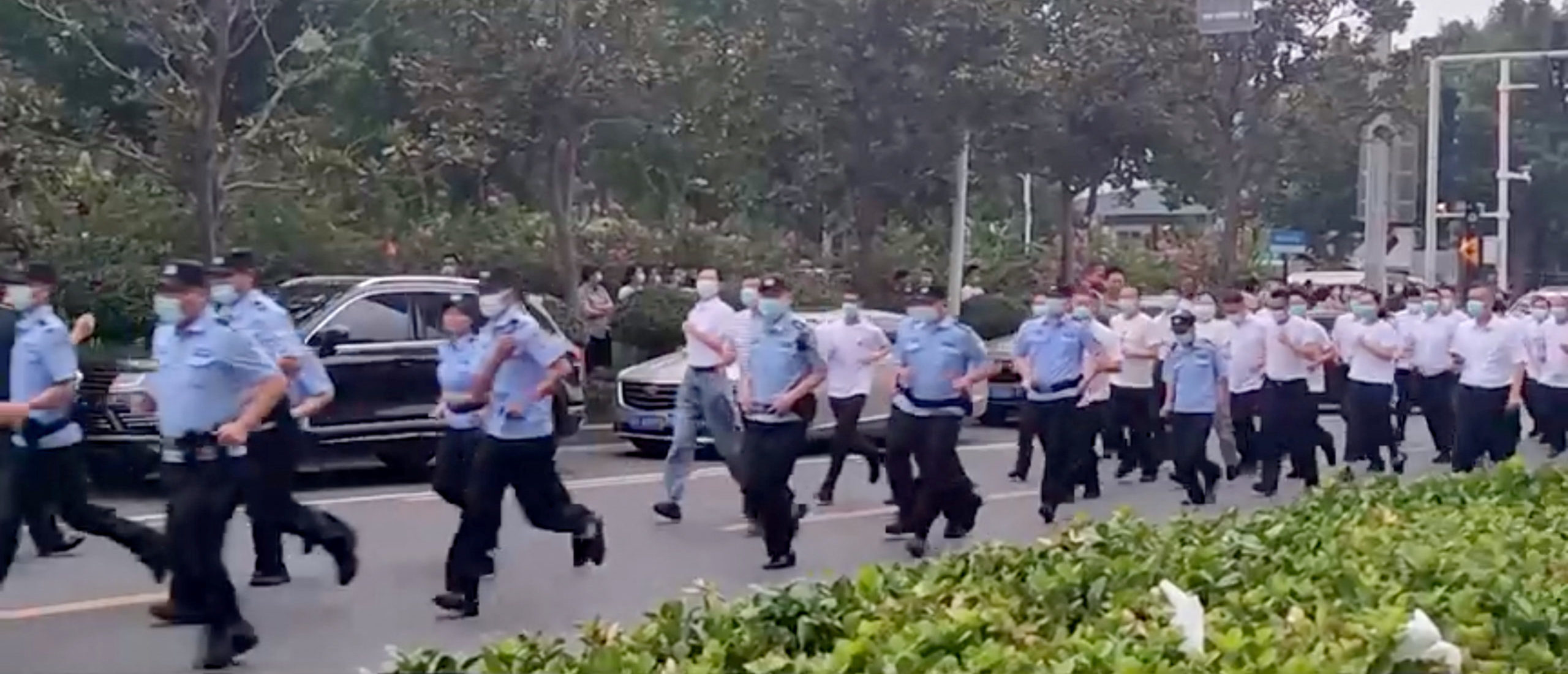 Uniformed and plain-clothed security personnel run to approach demonstrators, outside a People's Bank of China building, who are there protesting over the freezing of deposits by some rural-based banks, in Zhengzhou, Henan province, China July 10, 2022, in this screengrab from video obtained by Reuters. (Reuters)