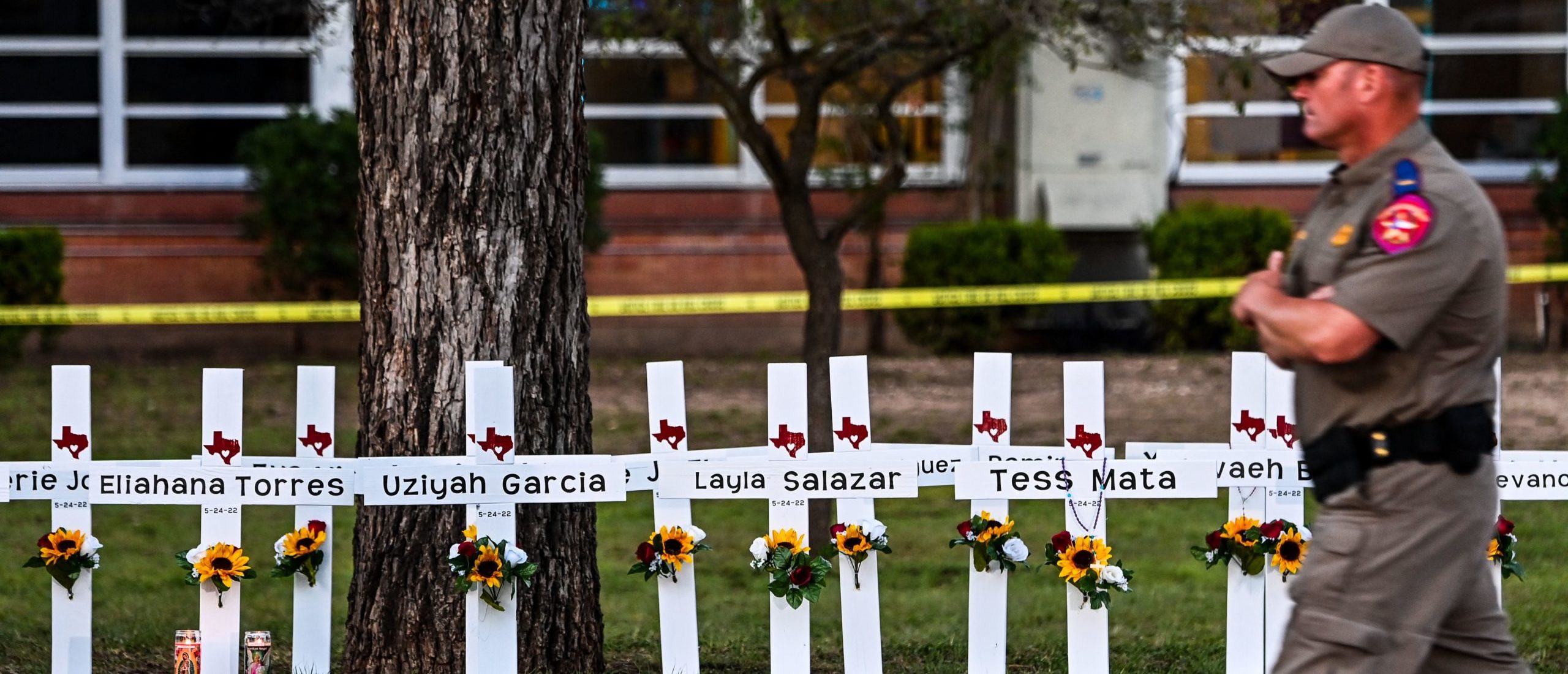 TOPSHOT - Police officers walk past a makeshift memorial for the shooting victims at Robb Elementary School in Uvalde, Texas, on May 26, 2022. - Grief at the massacre of 19 children at the elementary school in Texas spilled into confrontation on May 25, as angry questions mounted over gun control -- and whether this latest tragedy could have been prevented. The tight-knit Latino community of Uvalde on May 24 became the site of the worst school shooting in a decade, committed by a disturbed 18-year-old armed with a legally bought assault rifle. (Photo by CHANDAN KHANNA / AFP) (Photo by CHANDAN KHANNA/AFP via Getty Images)