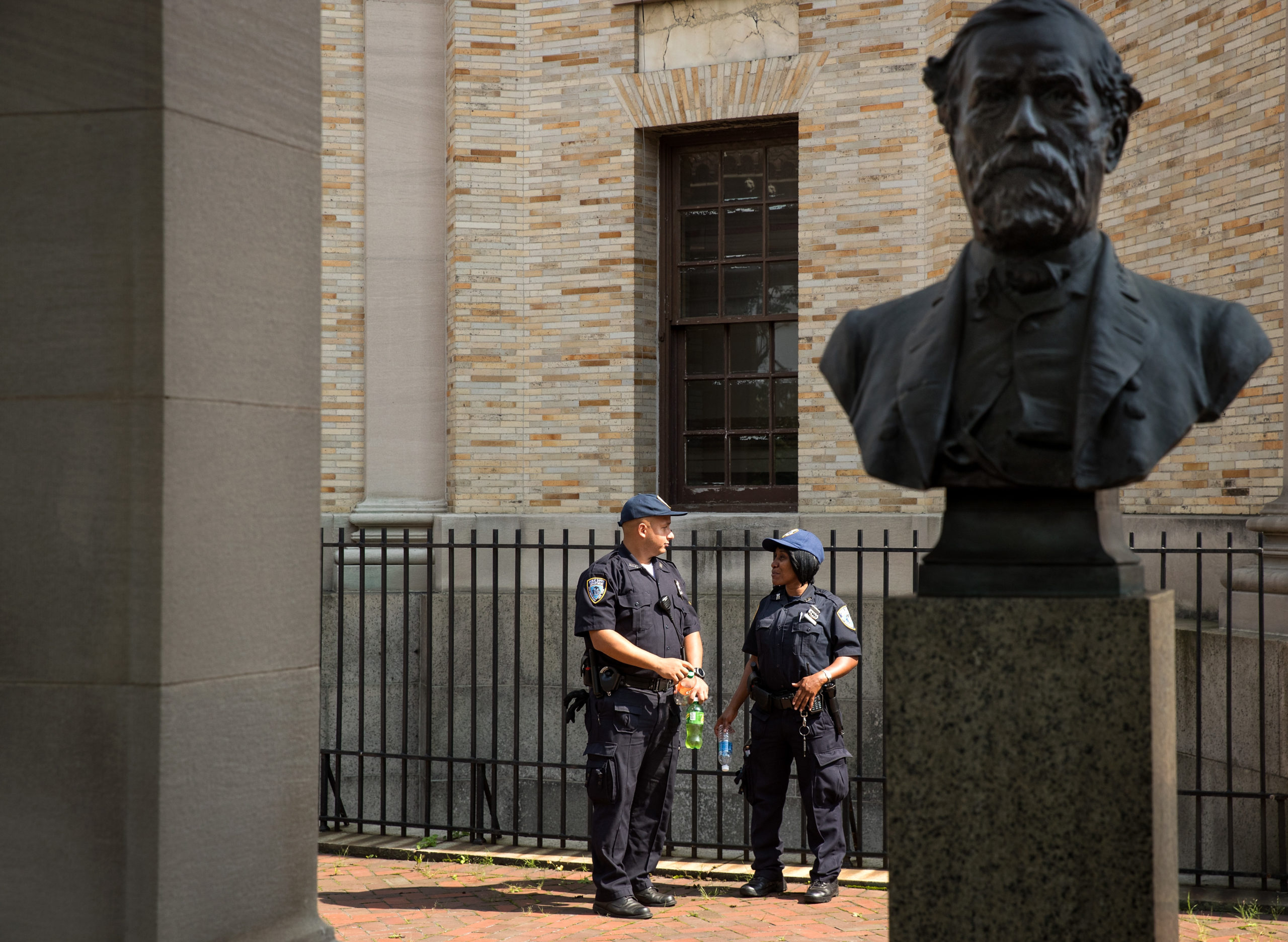 Two City University of New York Public Safety Department officers stand and monitor the area around a bust of Robert E. Lee as it stands in the 'Hall of Fame for Great Americans' on the campus of Bronx Community College, August 17, 2017 in the Bronx borough of New York City. On Wednesday night, the school announced the statues of Robert E. Lee and Confederate general Stonewall Jackson will be replaced and removed. (Photo by Drew Angerer/Getty Images)