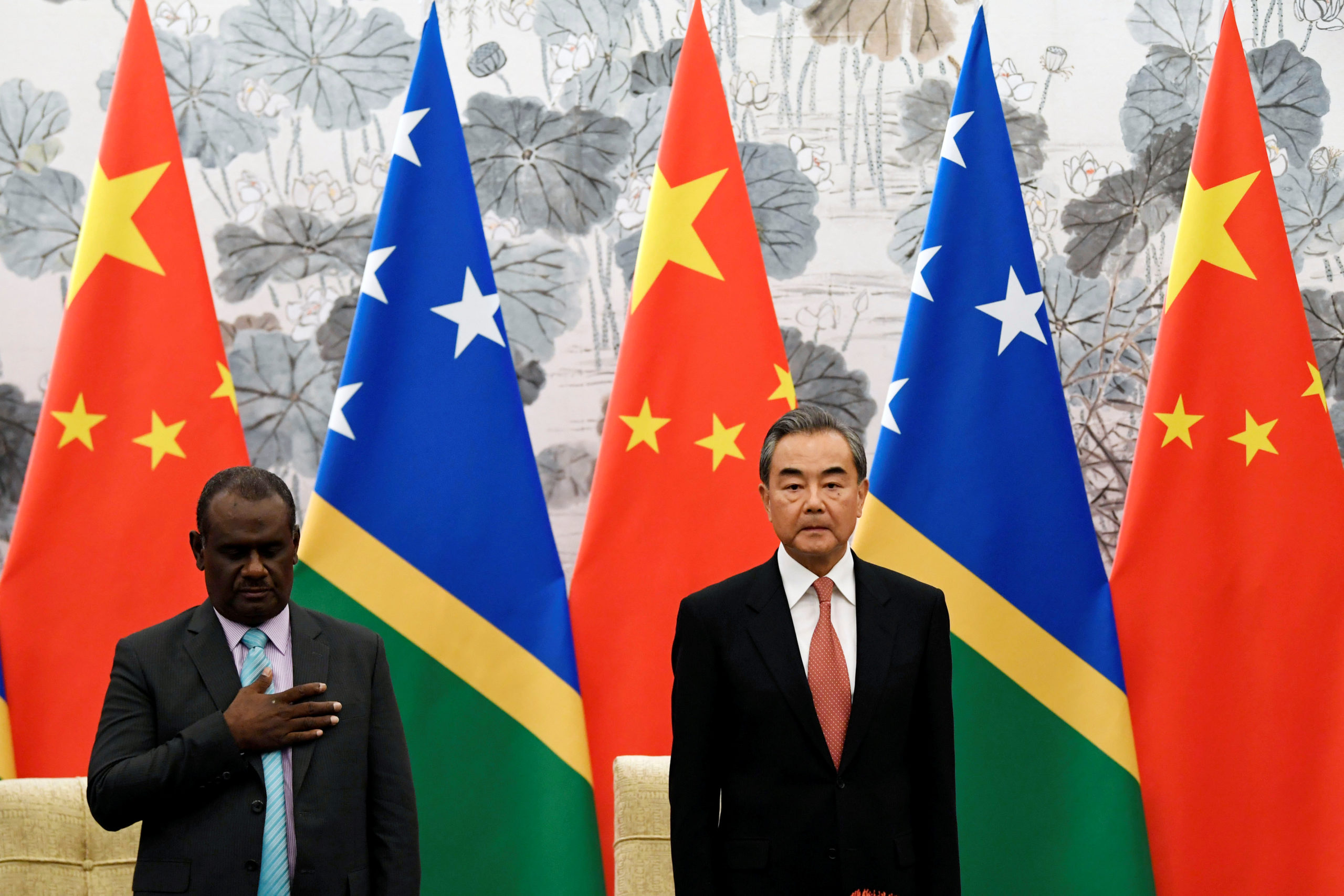 Chinese State Councilor and Foreign Minister Wang Yi and Solomon Islands Foreign Minister Jeremiah Manele listen to the Solomon Islands' national anthem during a ceremony to mark the establishment of diplomatic ties between the two nations at the Diaoyutai State Guesthouse in Beijing, China, September 21, 2019. 
