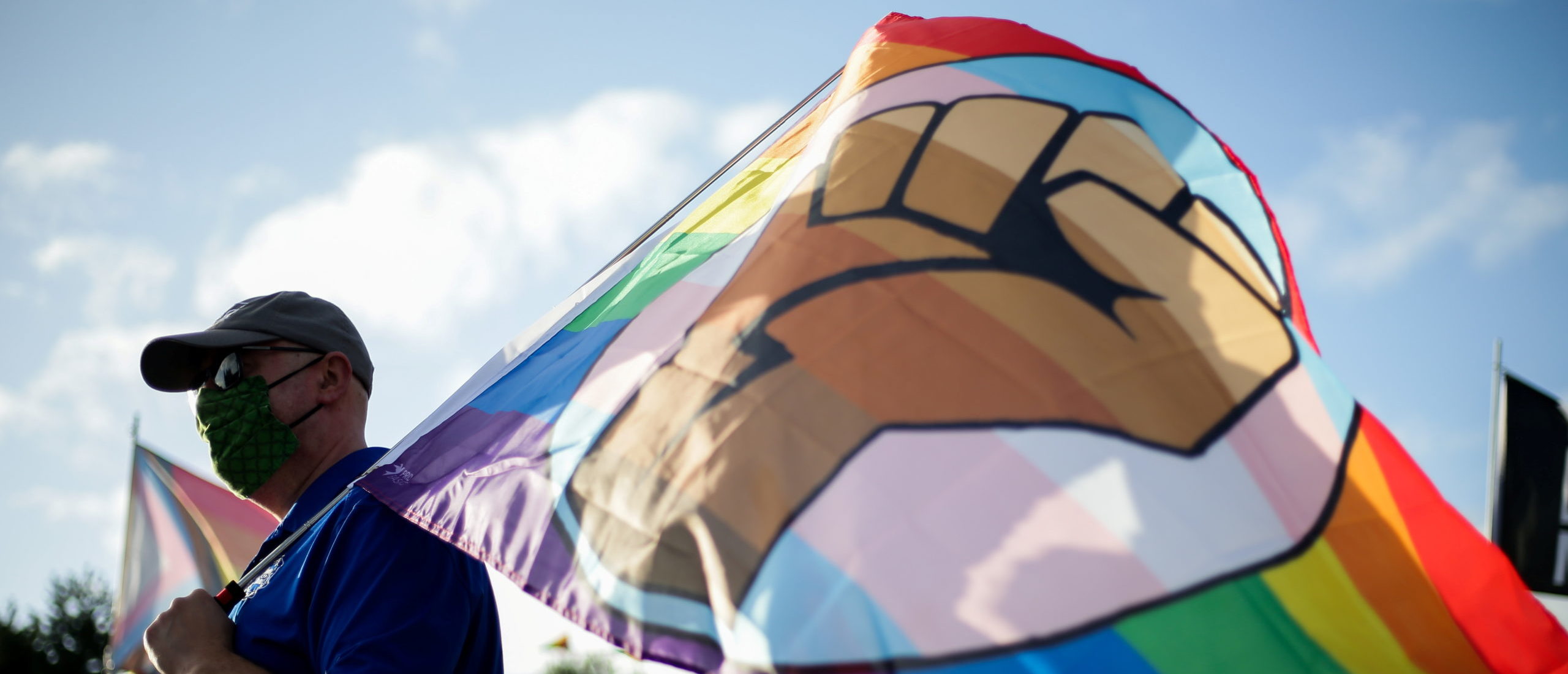 Matt Ogle of the Oregon Education Association holds a pride flag with a Black Lives Matter fist symbol as educators and supporters hold a rally to push back against the Newberg School Board's ban on educators displaying images or symbols that may be considered political or controversial, including LGBTQIA or Black Lives Matter symbols, in Newberg, Oregon, U.S. September 28, 2021. REUTERS/Lindsey Wasson
