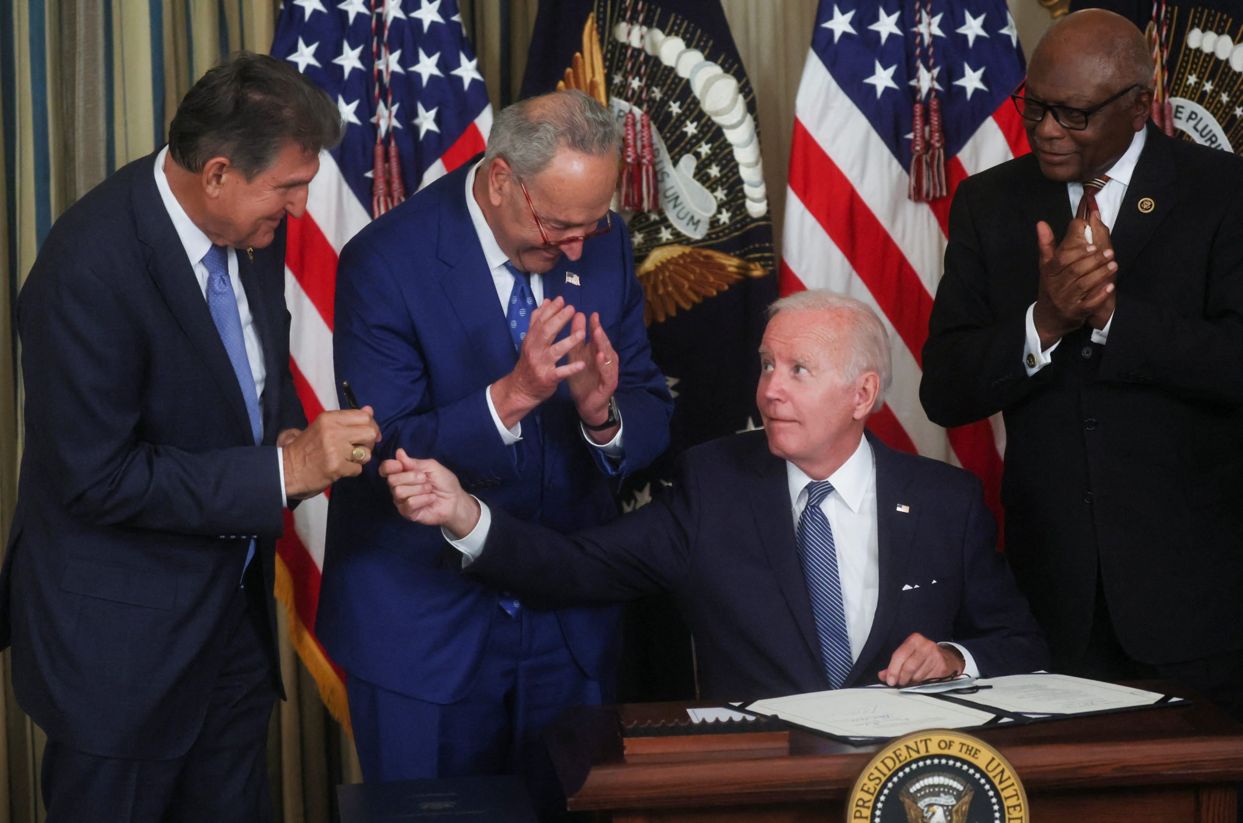 U.S. President Joe Biden hands his signing pen to U.S. Senator Joe Manchin (D-WV) as Senate Majority Leader Chuck Schumer (D-NY) and U.S. House Majority Whip James Clyburn (D-SC) look on immediately after Biden signed "The Inflation Reduction Act of 2022" into law during a ceremony in the State Dining Room of the White House in Washington, U.S. August 16, 2022. REUTERS/Leah Millis