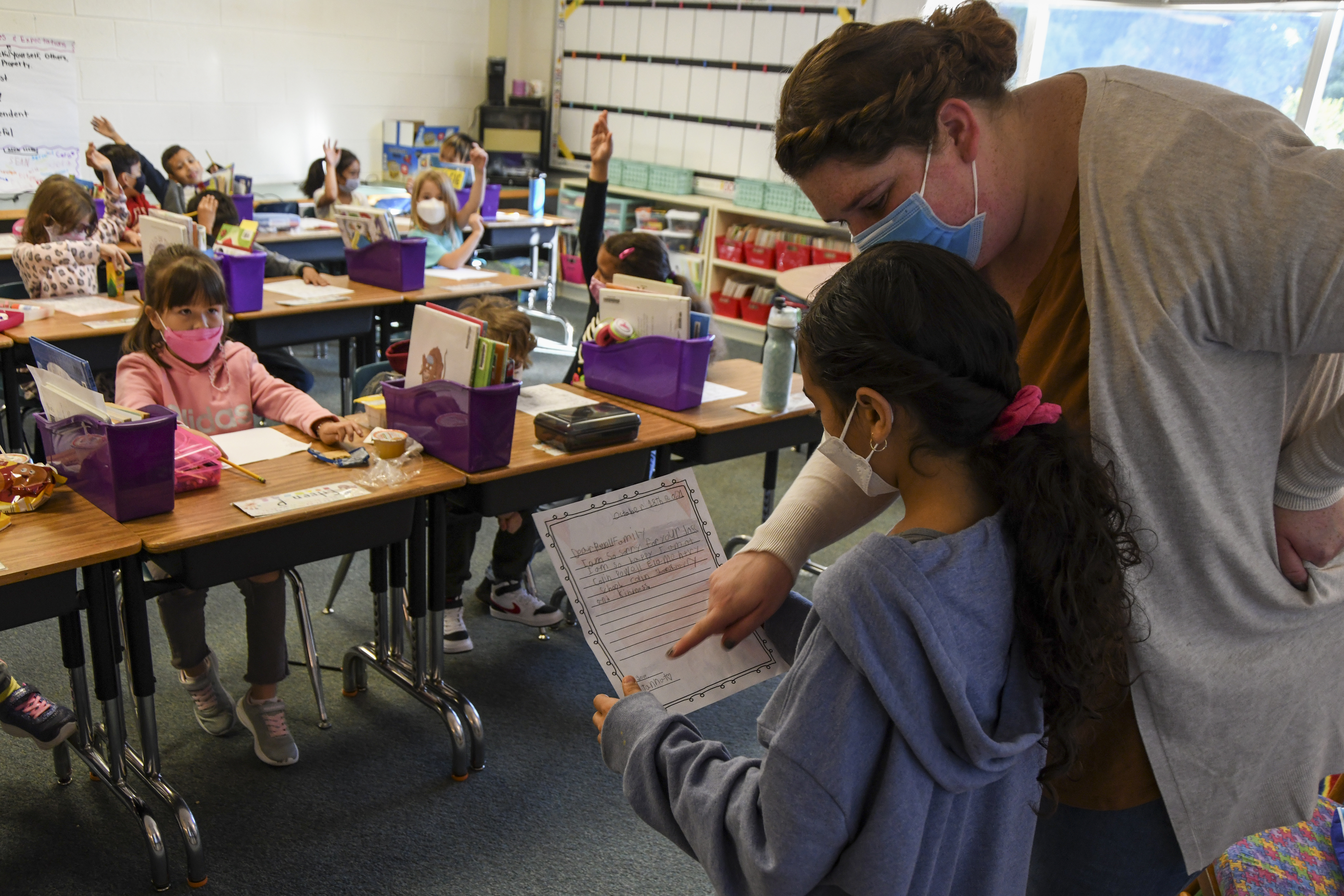 Kaitlin North, 2nd grade teacher at Colin L. Powell Elementary School, helps a student read aloud a letter they wrote to the family of Colin Powell with their condolences after news of his passing due to COVID-19 complications was announced, on October 19, 2021 in Centreville, Virginia. Students and faculty at the school, which is named after the former Secretary of State, honored his legacy by lowering the school's flag to half-staff, watching a video of Powell and holding a moment of silence. (Photo by Kenny Holston/Getty Images)