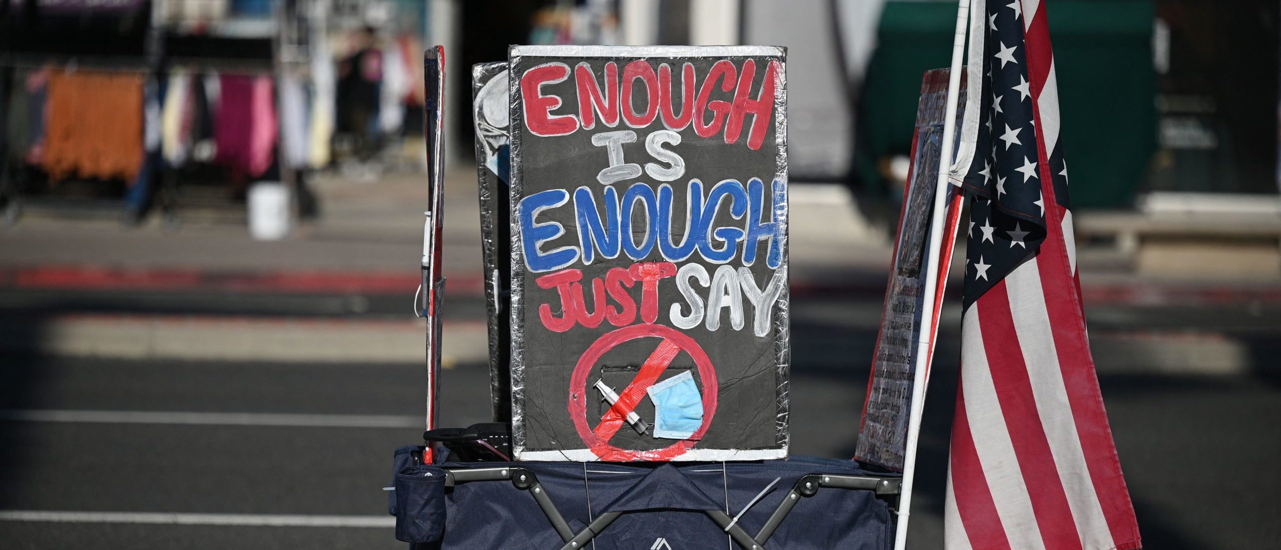 A display of a face mask and syringe with a circle and red line through it are seen at a protest against Covid-19 vaccine mandates for students, in Huntington Beach, California on January 3, 2022. - The Los Angeles Unified School District (LAUSD) announced in mid-December its decision to delay until fall 2022 its Covid-19 vaccine mandate for students 12 and older who attend class in person. The original deadline for in-person students to show proof of full vaccination was January 10, 2022. (Photo by Robyn Beck / AFP) (Photo by ROBYN BECK/AFP via Getty Images)