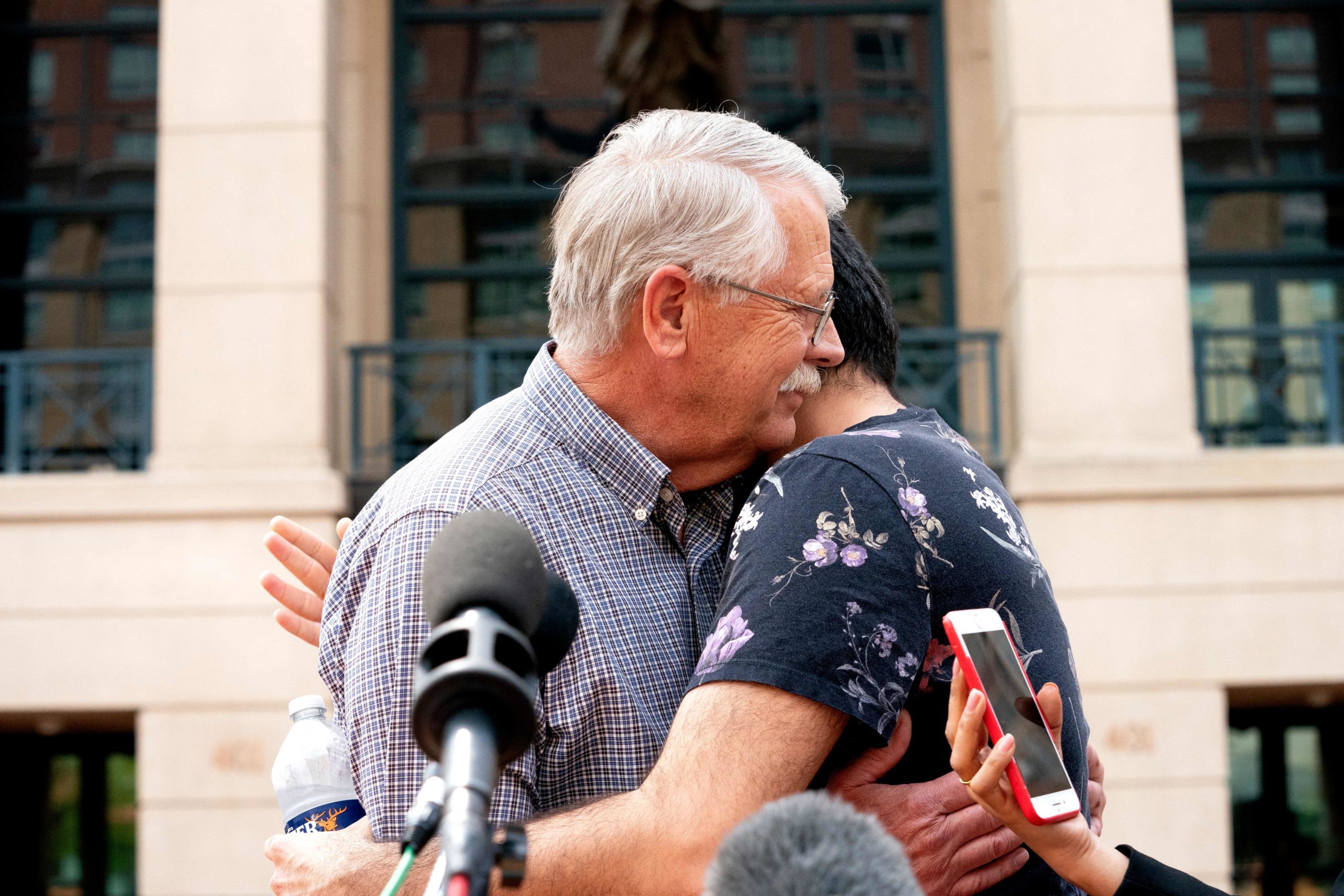 Carl Mueller, the father of Kayla Mueller, an American human rights activist slain by Islamic State militants, embraces Rodwan Safer Jalani, a friend of Kaylas, outside the Albert V. Bryan Federal Courthouse following the trial of IS member El Shafee Elsheikh, the Beatle, in Alexandria, Virginia, on April 14, 2022. - El Shafee Elsheikh, a member of the notorious Islamic State kidnap-and-murder cell known as the "Beatles," was found guilty of all charges on April 14, 2022 in the deaths of four American hostages in Syria. STEFANI REYNOLDS/AFP via Getty Images