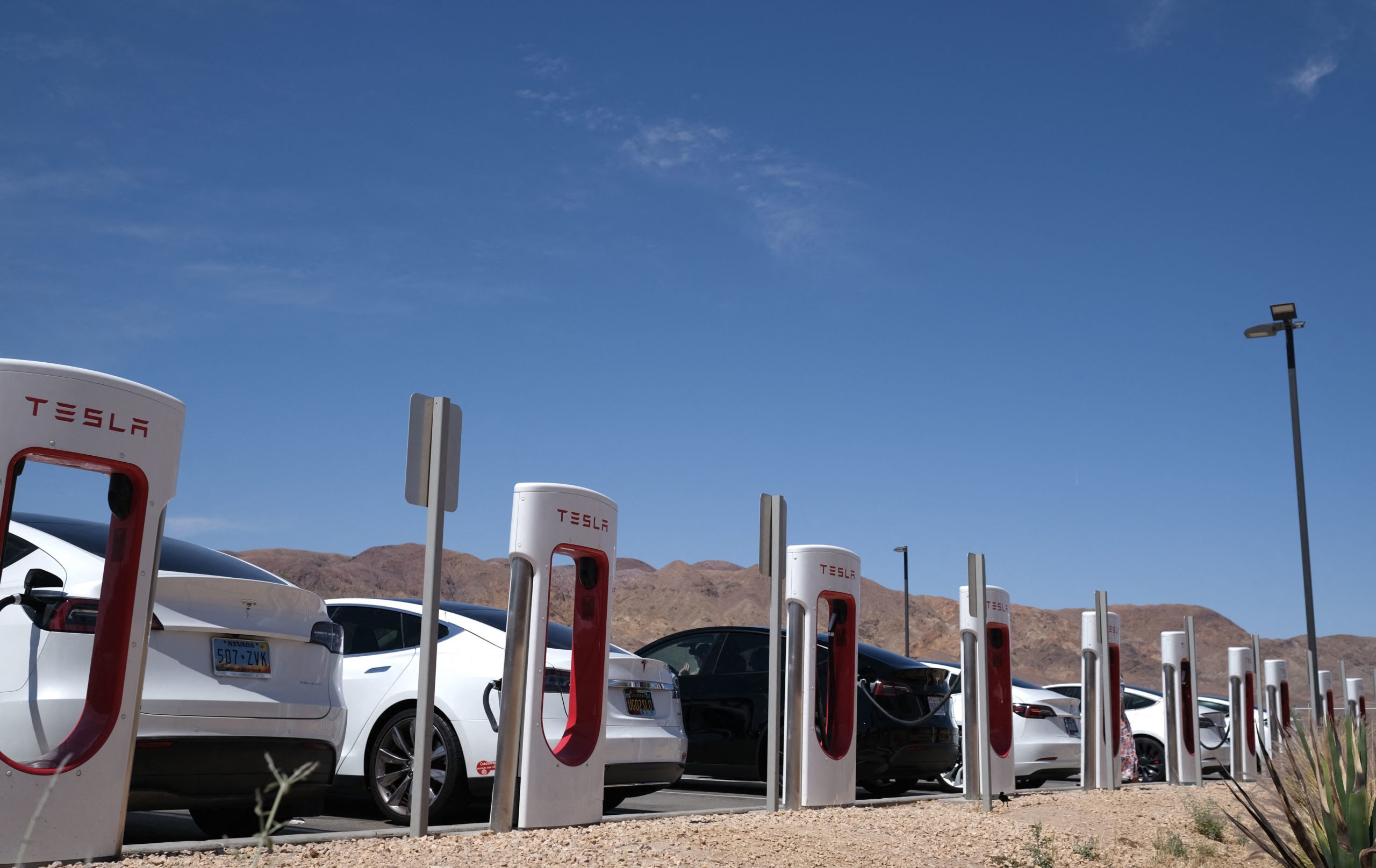 Tesla cars sit at charging stations in Yermo, California, on May 14, 2022. 