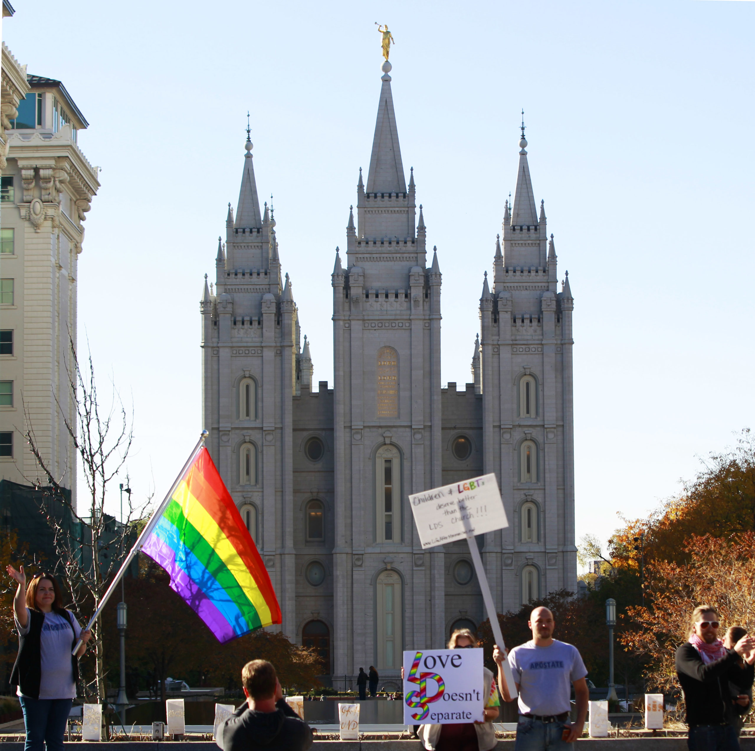 Protesters hold signs and a pride flag in front of the historic Mormon temple after many submitted their resignations from the Church of Jesus Christ of Latter-Day Saints in response to a recent change in church policy towards married LGBT same sex couples and their children on November 14, 2015 in Salt Lake City, Utah. A little over a week ago the Mormon church made a change in their official handbook of instructions requiring a disciplinary council and possible excommunication for same sex couples and banning the blessing and baptism of their children into the church. (Photo by George Frey/Getty Images)