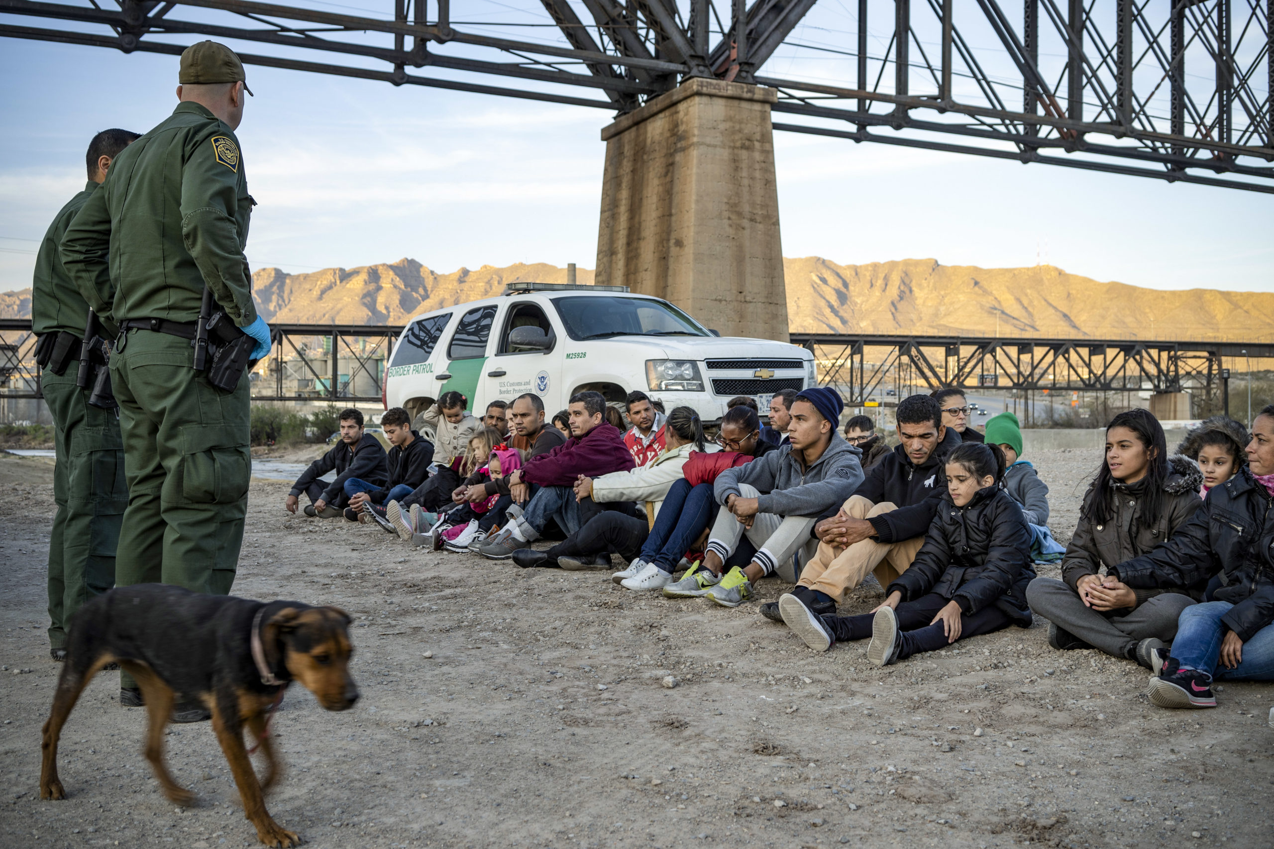 TOPSHOT - A group of about 30 Brazilian migrants, who had just crossed the border, sit on the ground near US Border Patrol agents, on the property of Jeff Allen, who used to run a brick factory near Mt. Christo Rey on the US-Mexico border in Sunland Park, New Mexico on March 20, 2019. - The militia members say they will patrol the US-Mexico border near Mt. Christo Rey, 