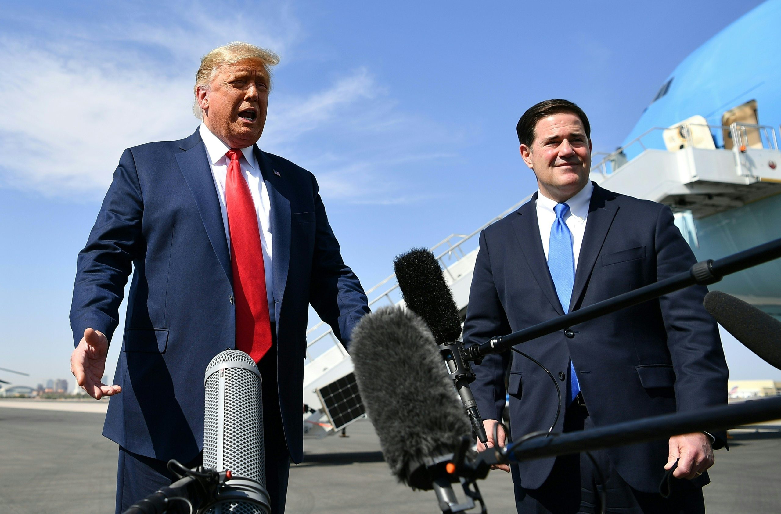 US President Donald Trump speaks to members of the media as Governor of Arizona Doug Ducey (R) looks on, upon arrival at Phoenix Sky Harbor International Airport in Phoenix, Arizona on October 19, 2020. Trump is heading to Prescott, Arizona for a campaign rally. - US President Donald Trump went after top government scientist Anthony Fauci in a call with campaign staffers on October 19, 2020, suggesting the hugely respected and popular doctor was an "idiot." (Photo by MANDEL NGAN / AFP) (Photo by MANDEL NGAN/AFP via Getty Images)