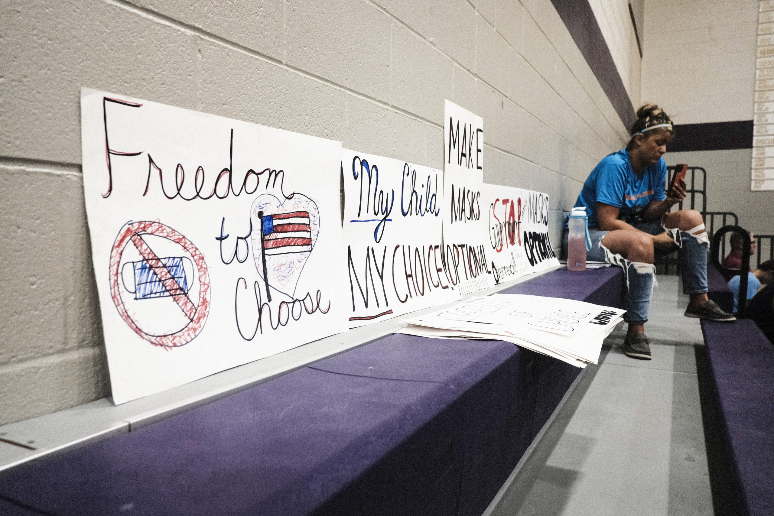 An attendee sits next to anti-vaccine mandate signs at a special Board of Education Meeting on mask mandates for students and staff in Kalamazoo County Schools at the Schoolcraft High School Gymnasium on August 23, 2021 in Schoolcraft, Michigan. The Schoolcraft Local School District opened the floor for public discussion. (Photo by Matthew Hatcher/Getty Images)