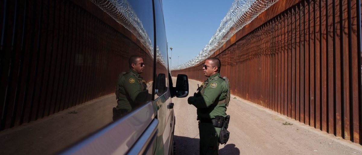 United States Border Patrol agent Carlos Rivera is reflected in the window of a vehicle as he speaks to another agent along the border wall in downtown El Paso, Texas on June 3, 2022. - (Photo by Paul Ratje / AFP) (Photo by PAUL RATJE/AFP via Getty Images)