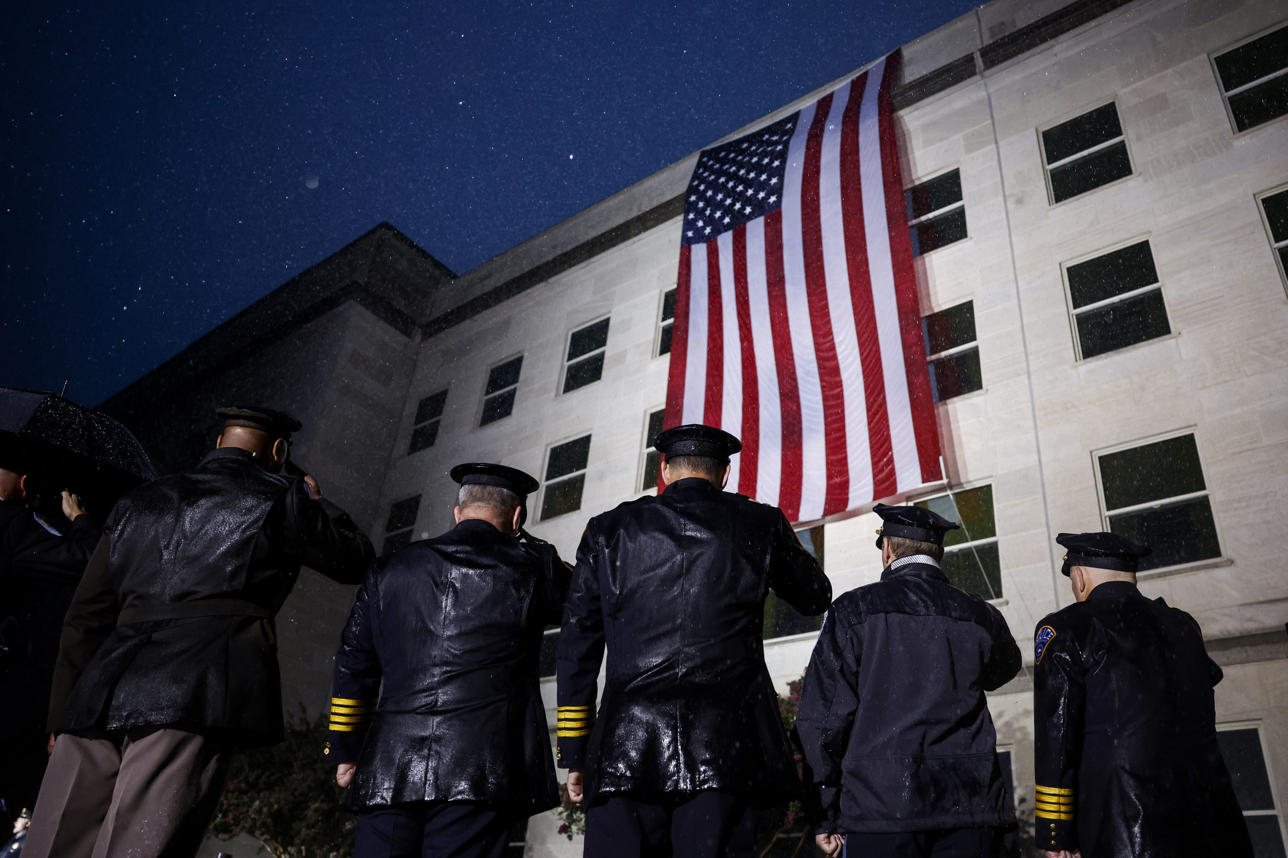 Members of the military and first responders stand in salute as an American flag is unfurled on the side of the Pentagon to commemorate the 21st anniversary of the 9/11 terror attacks on September 11, 2022 in Arlington, Virginia. Later today U.S. President Joe Biden will visit the Pentagon to participate in a wreath laying ceremony and give remarks to honor and remember the victims of the September 11th terror attack. (Photo by Anna Moneymaker/Getty Images)