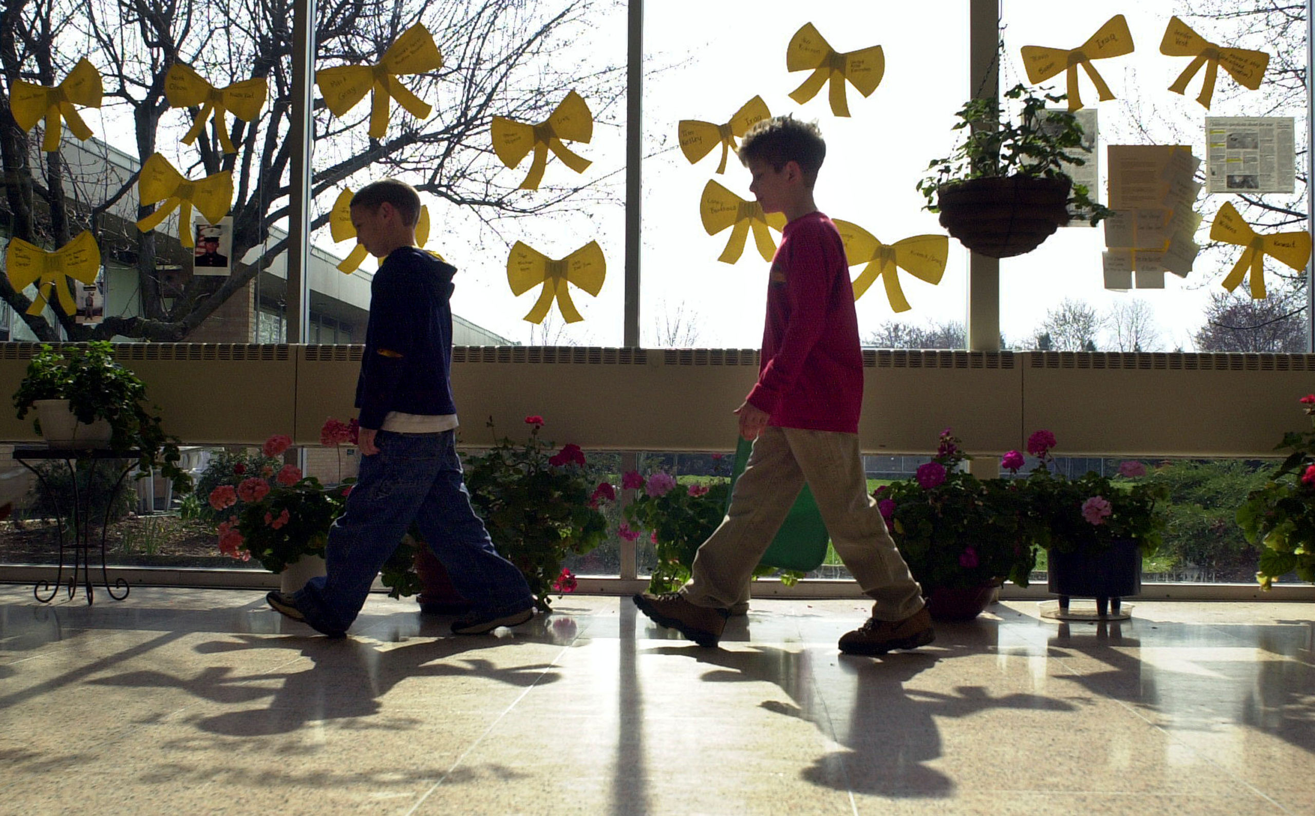 Students walk past yellow ribbons taped to windows at Longstreth Elementary School in support of military family members involved in the U.S.-led war with Iraq April 2, 2003 in Warminster, Pennsylvania. The cards will be taken home to the students' parents to be sent to the military family members through the USO. One third of the student population at Longstreth has a family member in a U.S. military service stationed at the Willow Grove Naval Air Station in Horsham, Pennsylvania. (Photo by William Thomas Cain/Getty Images)