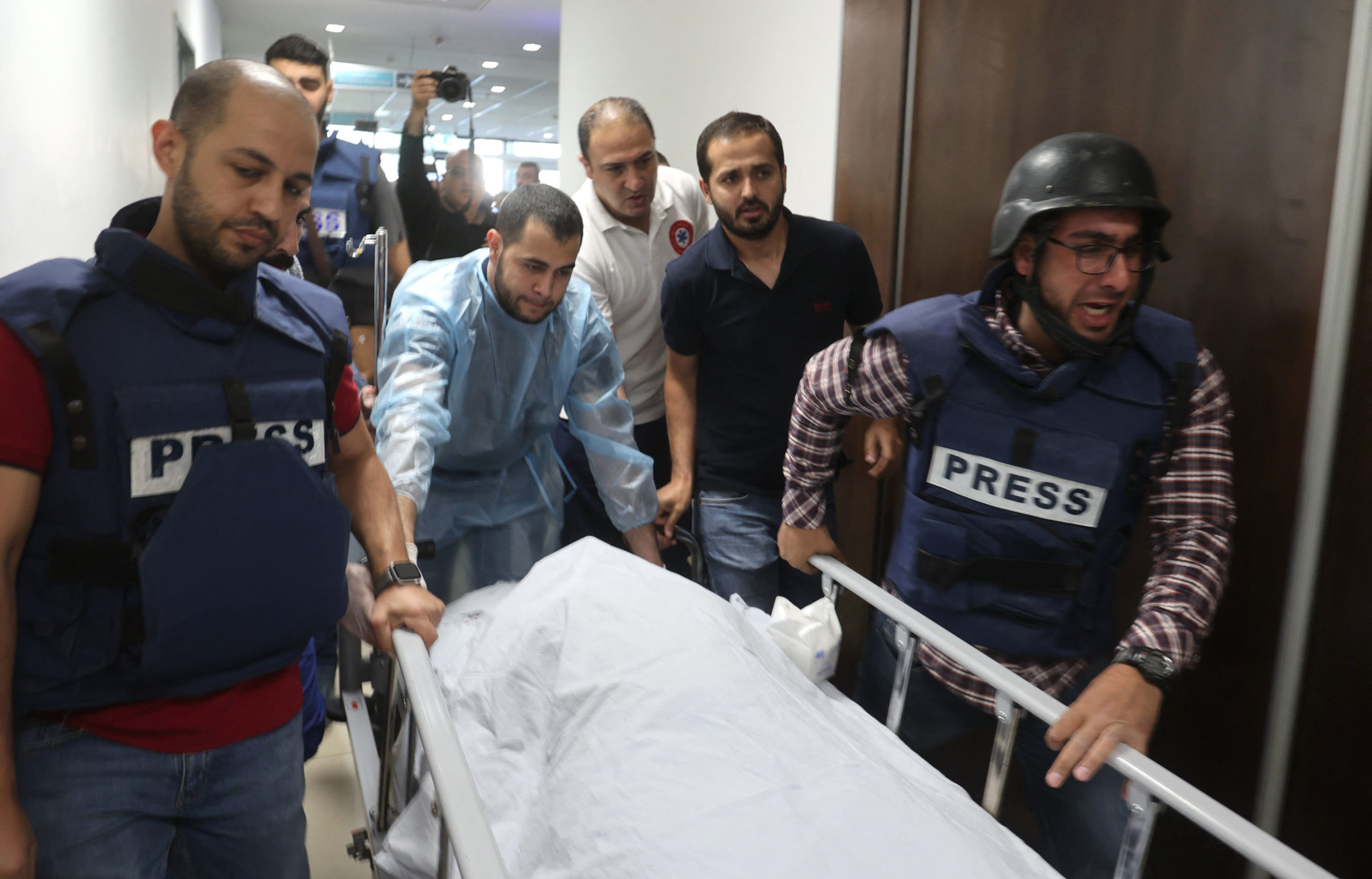 TOPSHOT - Palestinian cameraman Mujahed al-Saadi (C-L) of Palestine Today TV weeps as he escorts with other journalists the body of veteran Al-Jazeera reporter Shireen Abu Aqleh (Akleh), who was shot dead as she covered a raid on the West Bank's Jenin refugee camp, on May 11, 2022, at the hospital in Jenin. - Abu Aqleh, 51, a prominent figure in the channel's Arabic news service was shot dead on May 11 as she covered an Israeli army raid on Jenin refugee camp in the occupied West Bank. The Qatar-based TV channel said Israeli forces shot Abu Aqleh deliberately and "in cold blood" while Israeli Prime Minister Naftali Bennett said it was "likely" that Palestinian gunfire killed her.