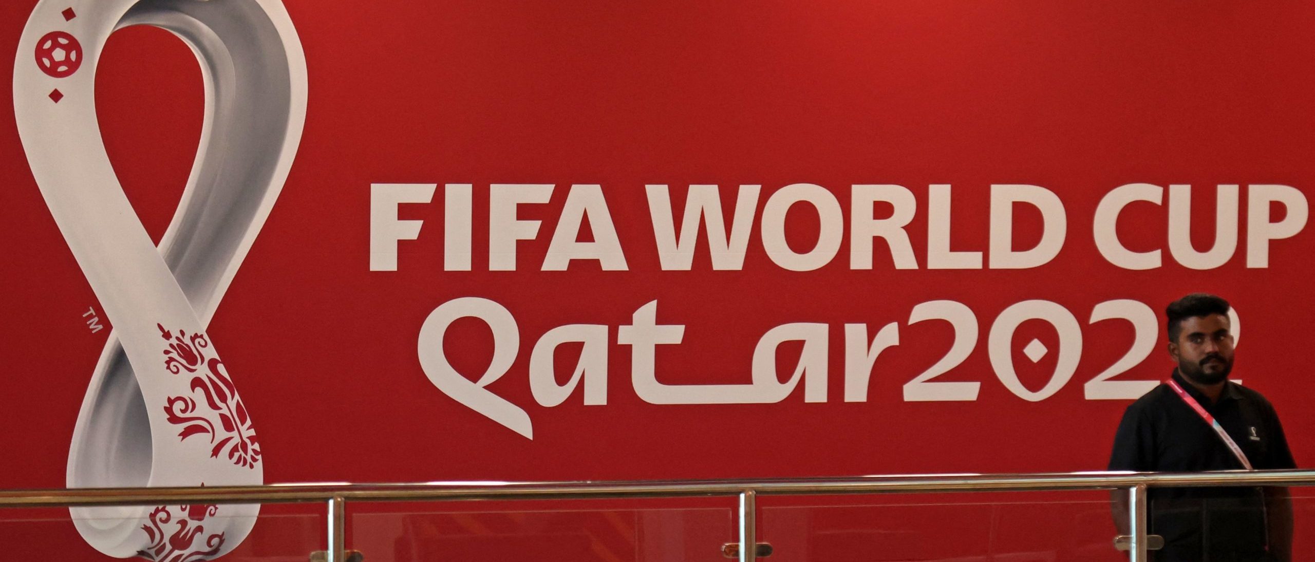 An employee stands in front of the logo of Qatar 2022 FIFA World Cup football tournament at the Host Country Media Centre in Doha on November 3, 2022. (Photo by KARIM JAAFAR/AFP via Getty Images)