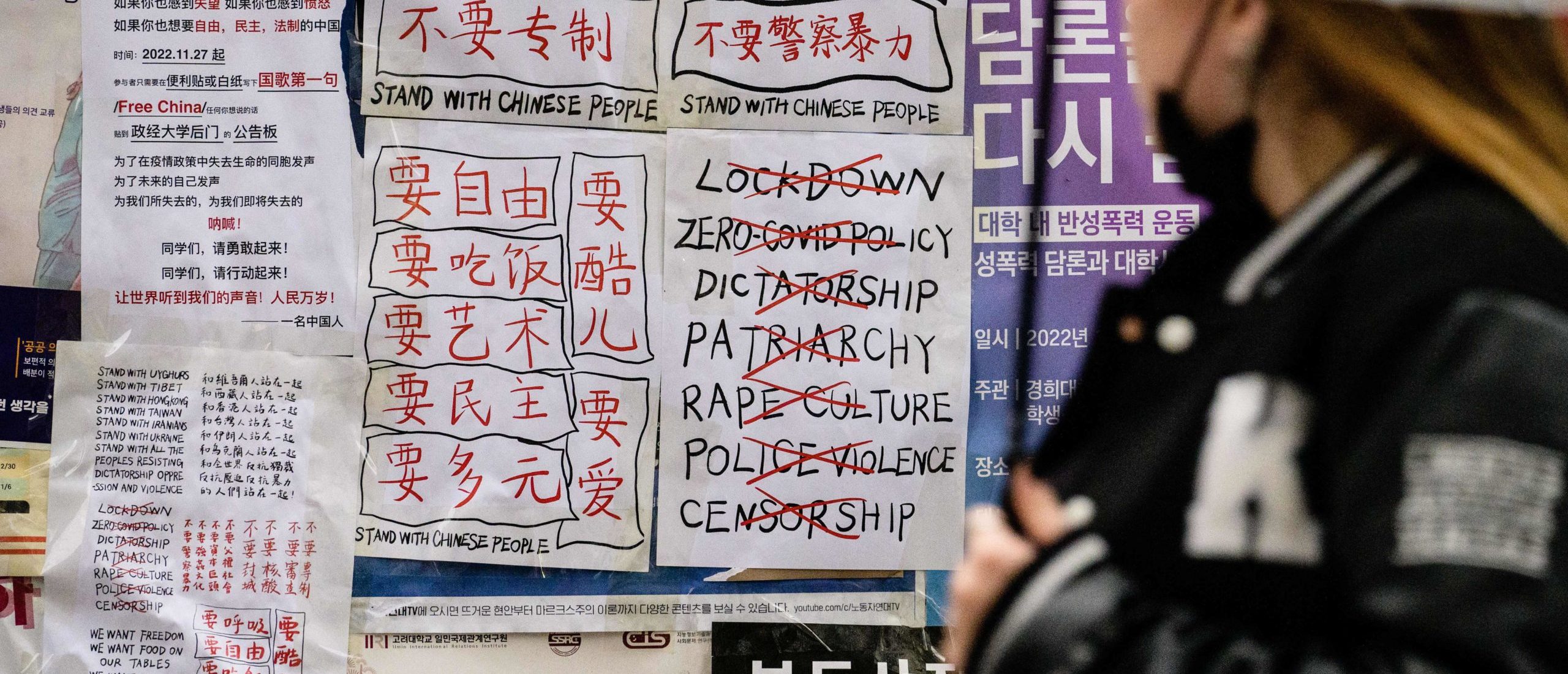 A student glances at anti-Chinese government posters displayed outside a university in Seoul on November 28, 2022, following protests over China's zero-Covid policy on the streets of some of its biggest cities calling for an end to lockdowns and greater political freedoms.