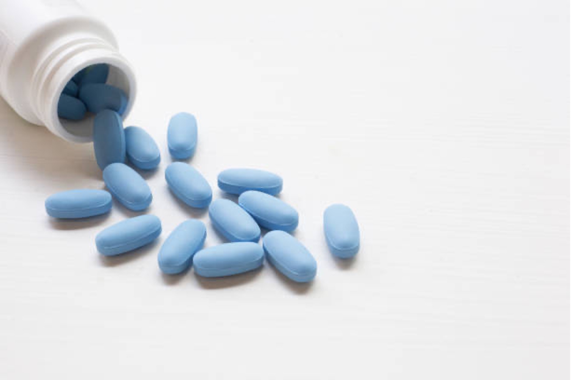 blue pills spilling from a white medicine bottle
