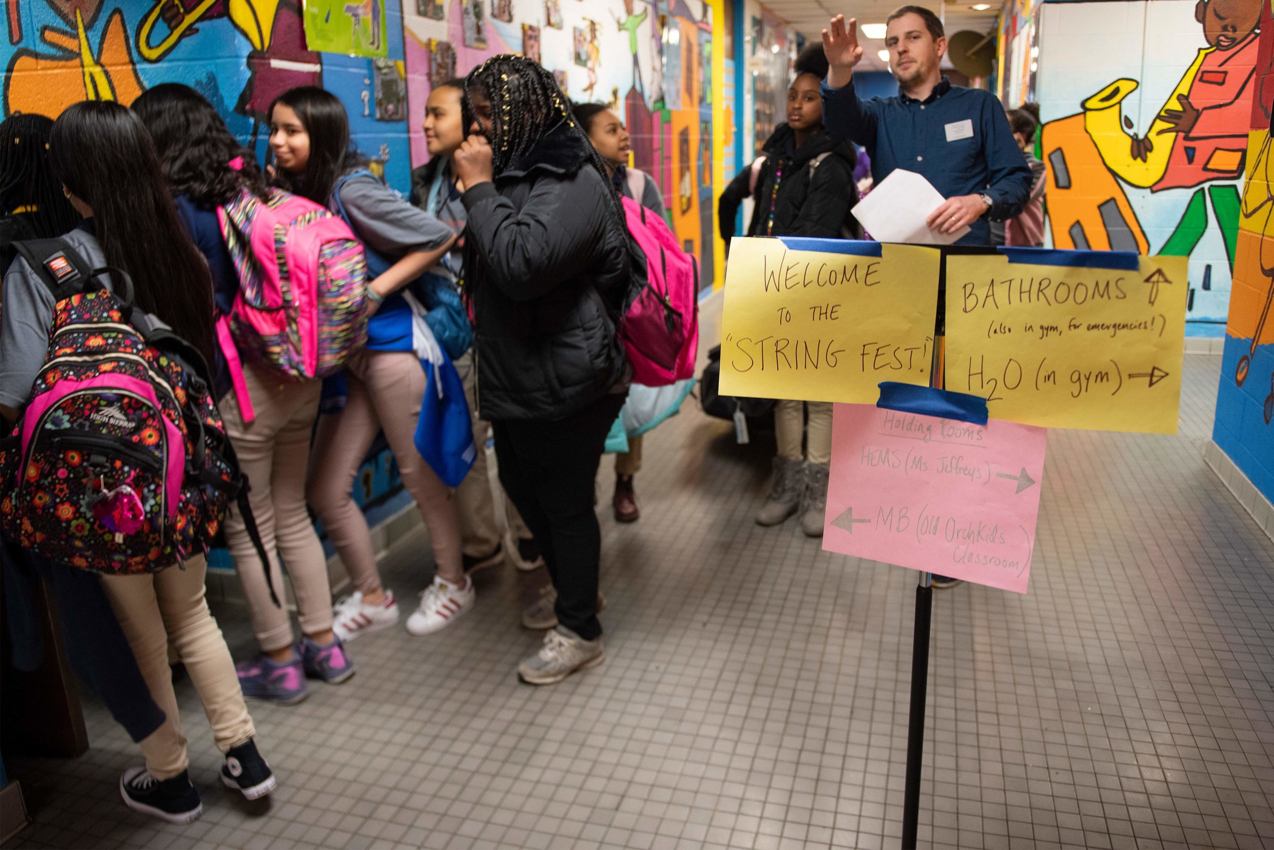 A teacher directs students to their rooms to get their instruments for the Baltimore Symphony Orchestra's OrchKids program during the String Fling concert at the Lockerman Bundy Elementary School in Baltimore, Maryland, on March 12, 2019. - As the conductor raises her baton, dozens of children come to order, and their everyday cacophonous chatting gives way to a melodic cascade of notes. The 60 or so students are part of OrchKids, a program run by the Baltimore Symphony Orchestra, which is hoping to bring change to the troubled city through the power of music. (Photo by Jim WATSON / AFP) (Photo credit should read JIM WATSON/AFP via Getty Images)