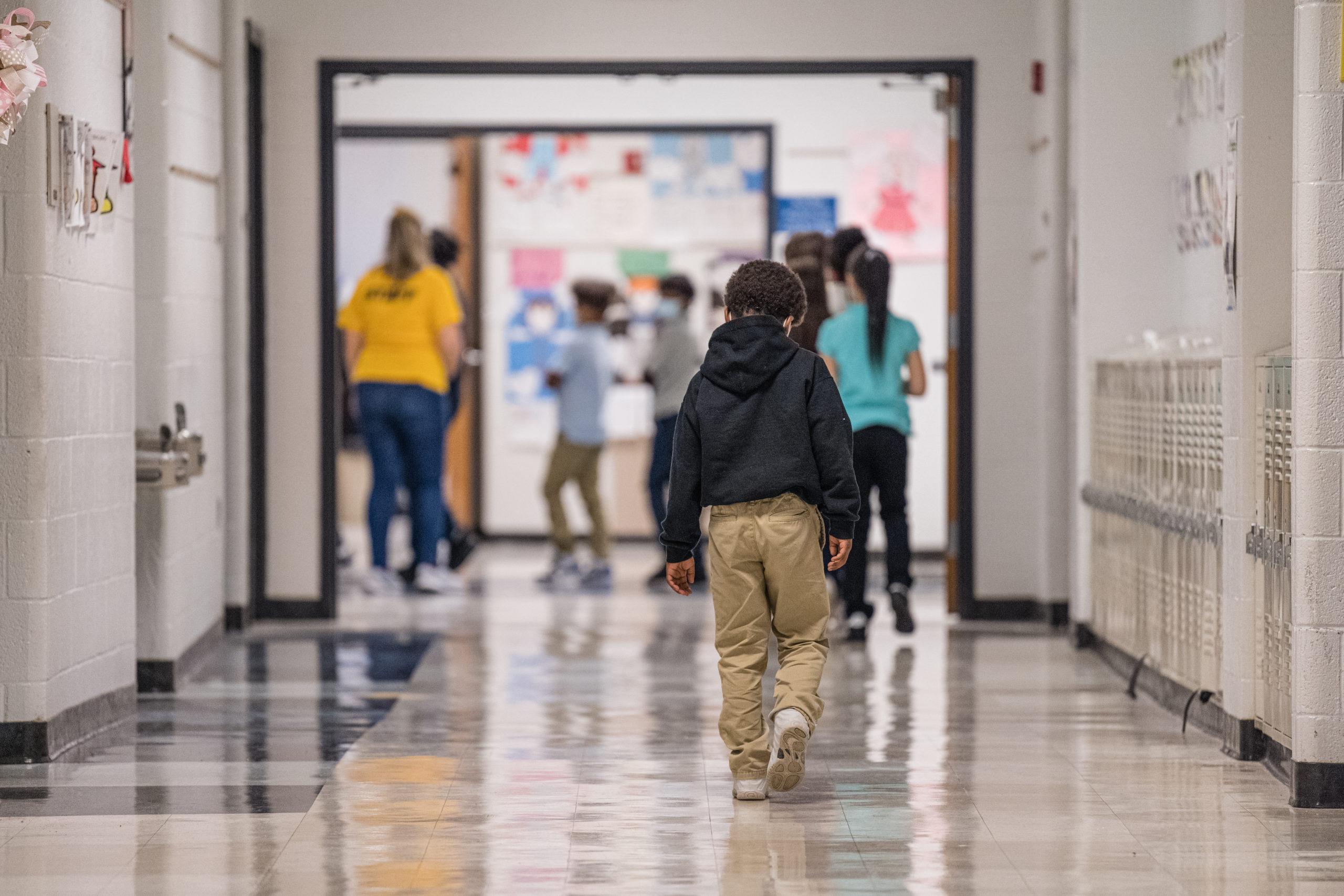 A young boy walks down a hallway at Carter Traditional Elementary School on January 24, 2022 in Louisville, Kentucky. Students in the district are returning to in-person class after two weeks of Non-Traditional Instruction (NTI) due to staffing issues caused by a surge of the COVID-19 omicron variant. (Photo by Jon Cherry/Getty Images)