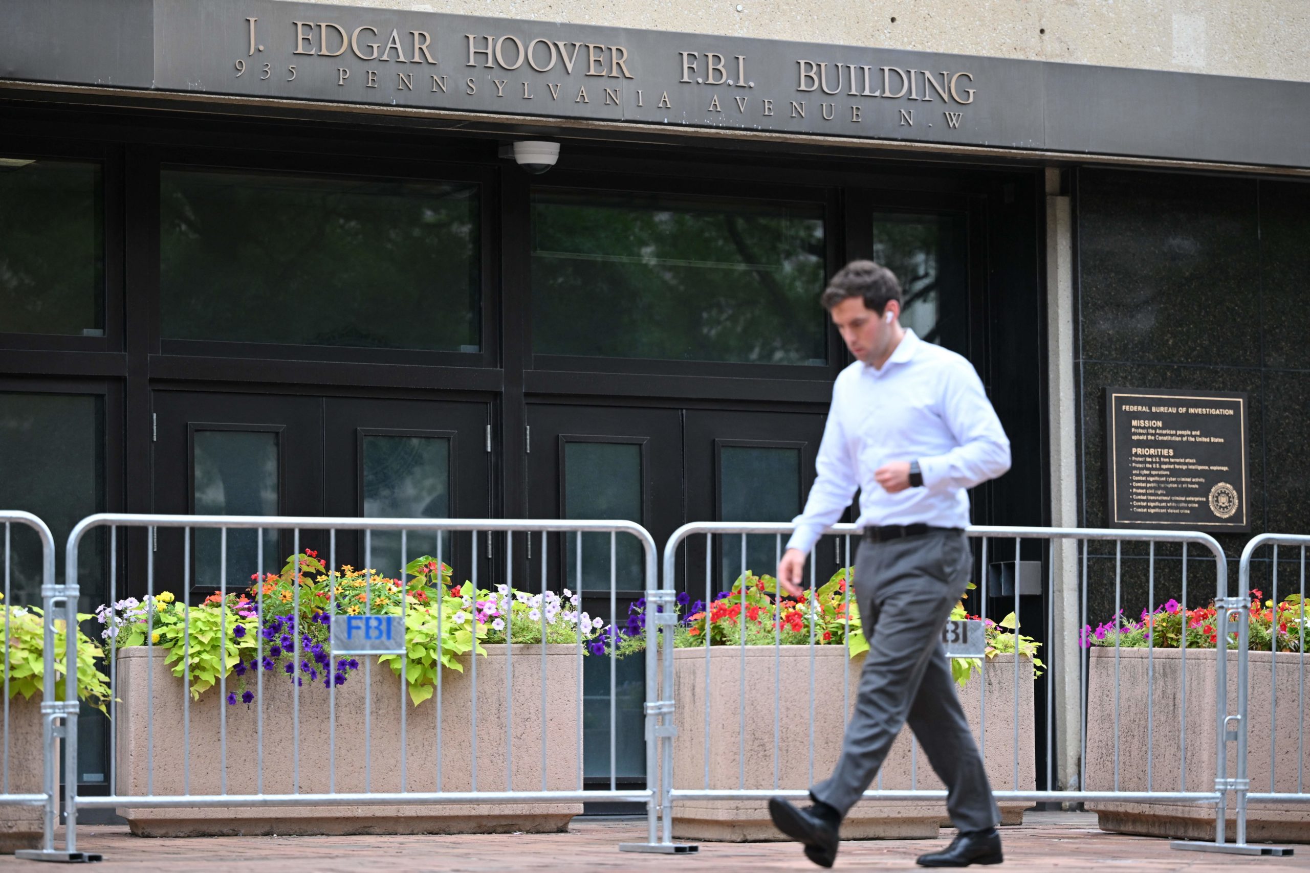 A pedestrian walks past police barricades surrounding the J. Edgar Hoover FBI building in Washington, DC, on August 15, 2022. (Photo by MANDEL NGAN / AFP) (Photo by MANDEL NGAN/AFP via Getty Images)